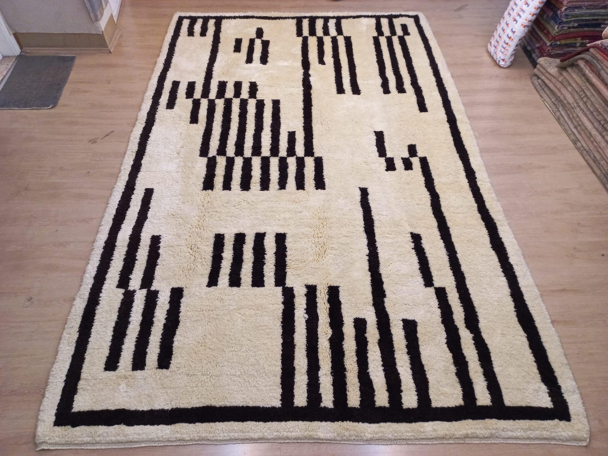 Eleva tu espacio vital con el exquisito encanto de esta nueva y moderna alfombra bereber marroquí beni ourain anudada a mano, elaborada con precisión y cuidado a partir de 100% lana. Combinando el encanto del diseño marroquí con la sensibilidad
