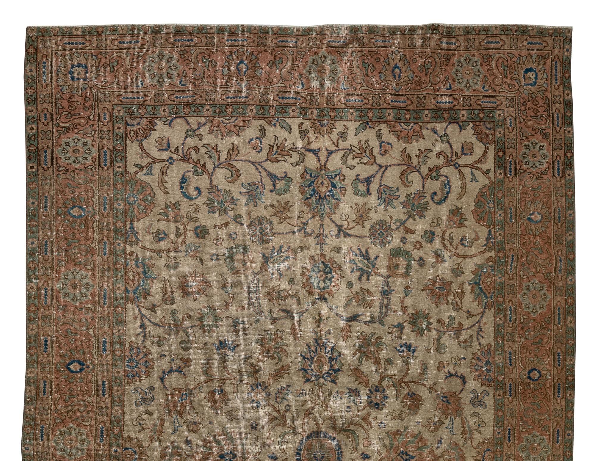 A vintage hand-knotted Oushak area rug from Central Turkey featuring an all-over design of lush scrolling vines decorated with finely detailed leaves, palmettes and rosettes in cerulean green, navy blue and dark coral pink against a stone beige