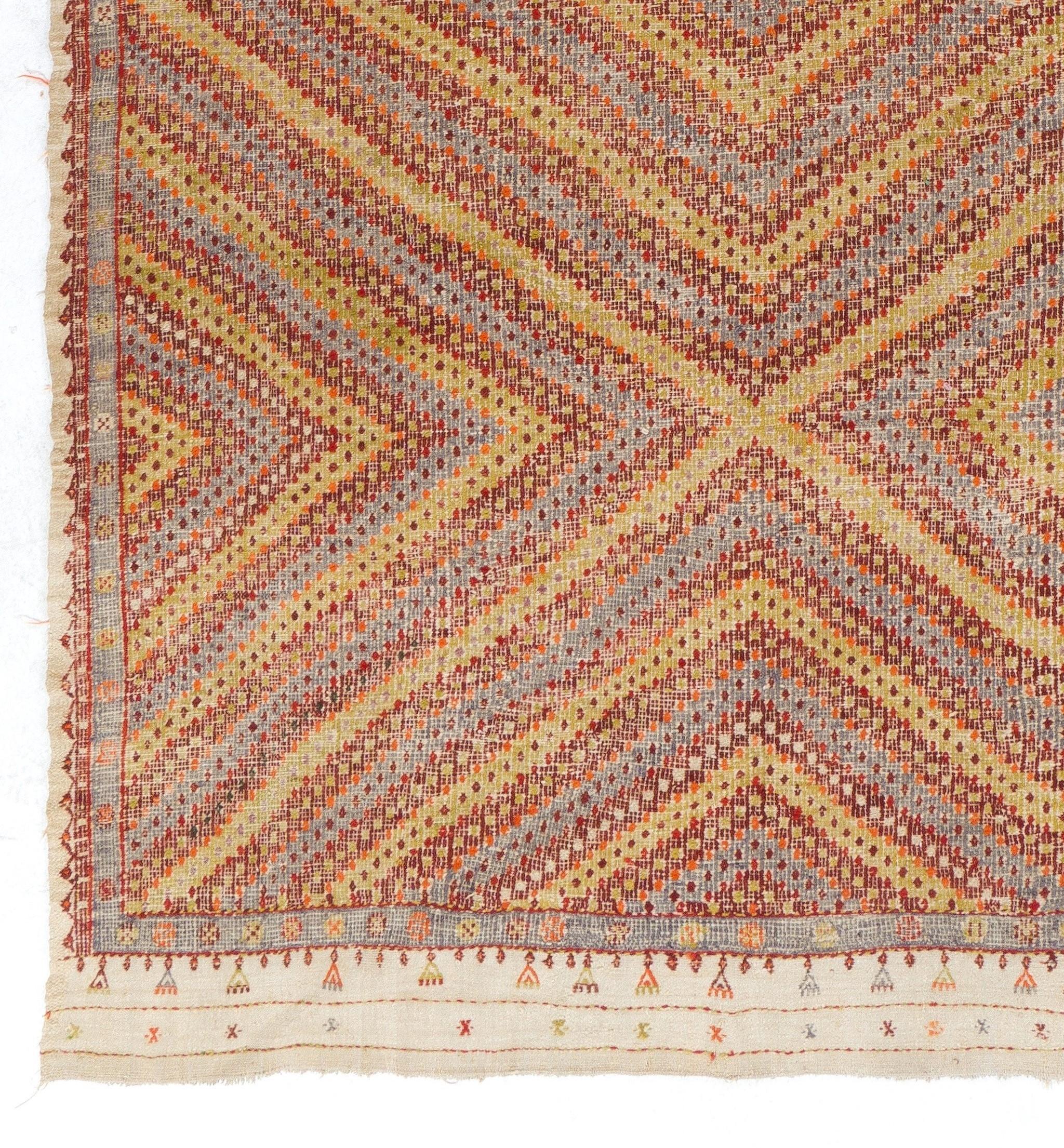 Ce tapis turc vintage unique en son genre, tissé à plat, présente un délicat motif géométrique composé de losanges imbriqués dont les contours et les sections médianes sont minutieusement parsemés d'autres losanges minimes. L'esthétique magnifique