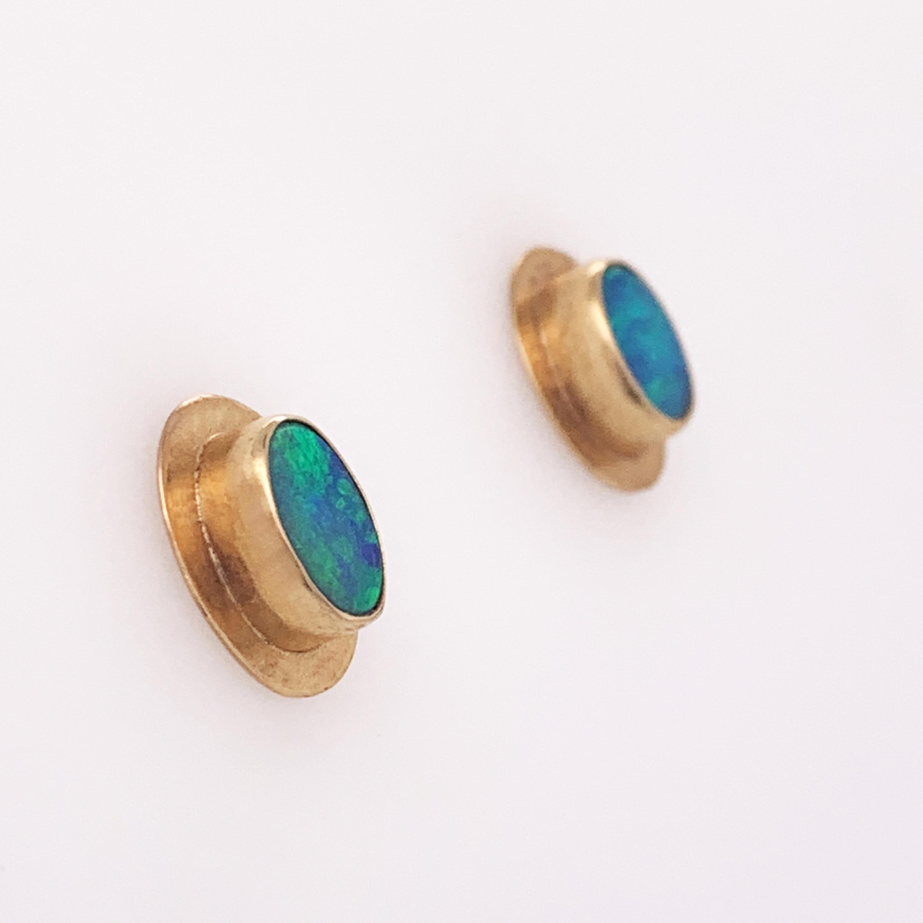 These small opal earrings look as if they walked directly out of the 80's. The stunning and complimentary look of natural blue opals set in yellow gold is such a fun vintage style. Each earring centers around a small flat oval natural opal framed by