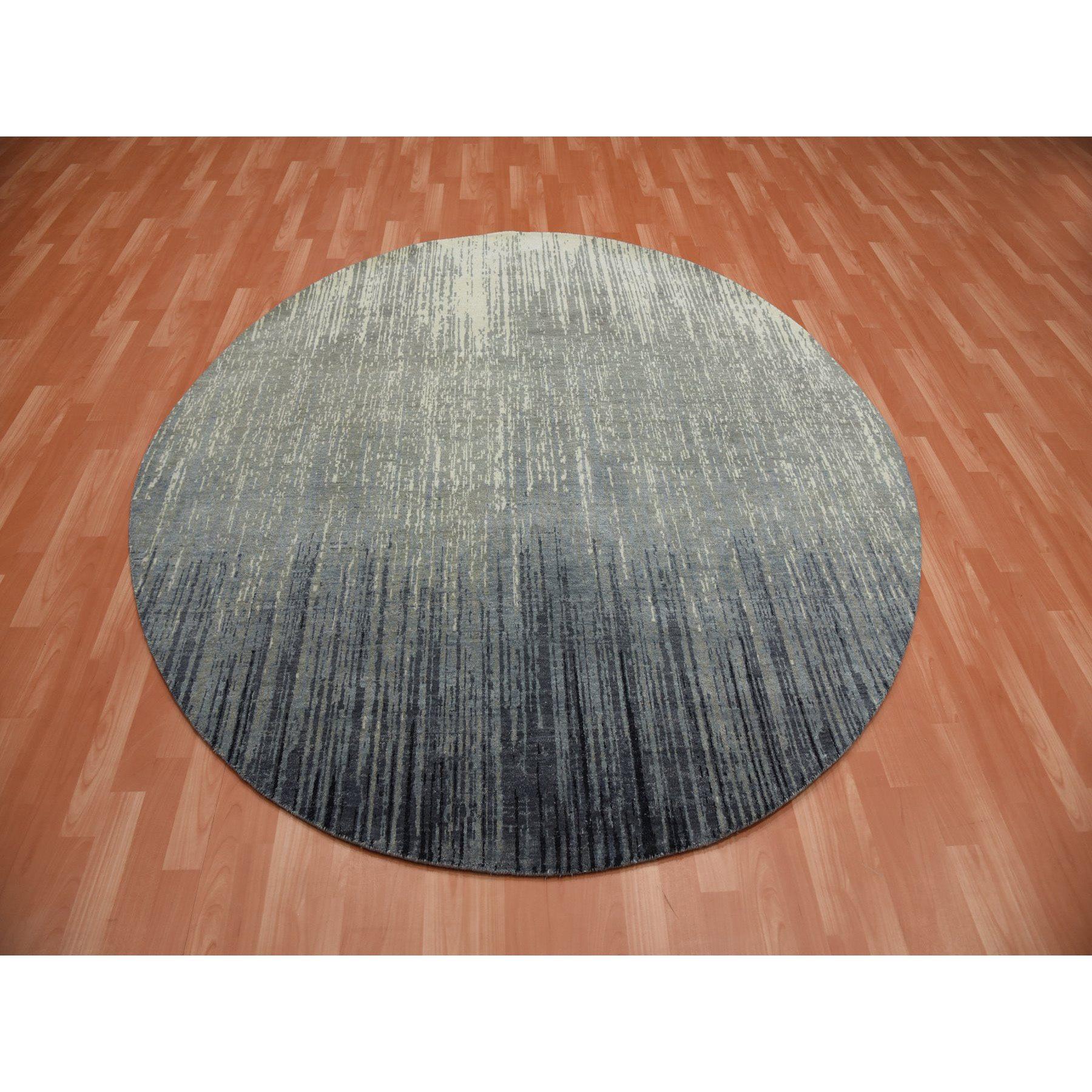Il s'agit d'un véritable tapis oriental rond en pure laine, gris et noir, densément tissé à la main, avec un design moderne en forme d'ombre. Il a été noué pendant des mois et des mois selon des techniques de tissage séculaires par des artisans