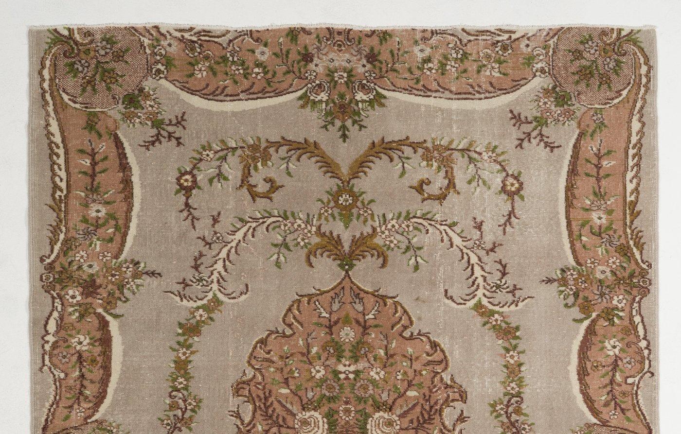 Vintage hand-knotted Turkish rug with low wool pile on cotton foundation with a French-Aubusson inspired design of floral bouquets and wreaths in faded rose and light taupe gray. The rug is in very good condition, sturdy, professionally cleaned and