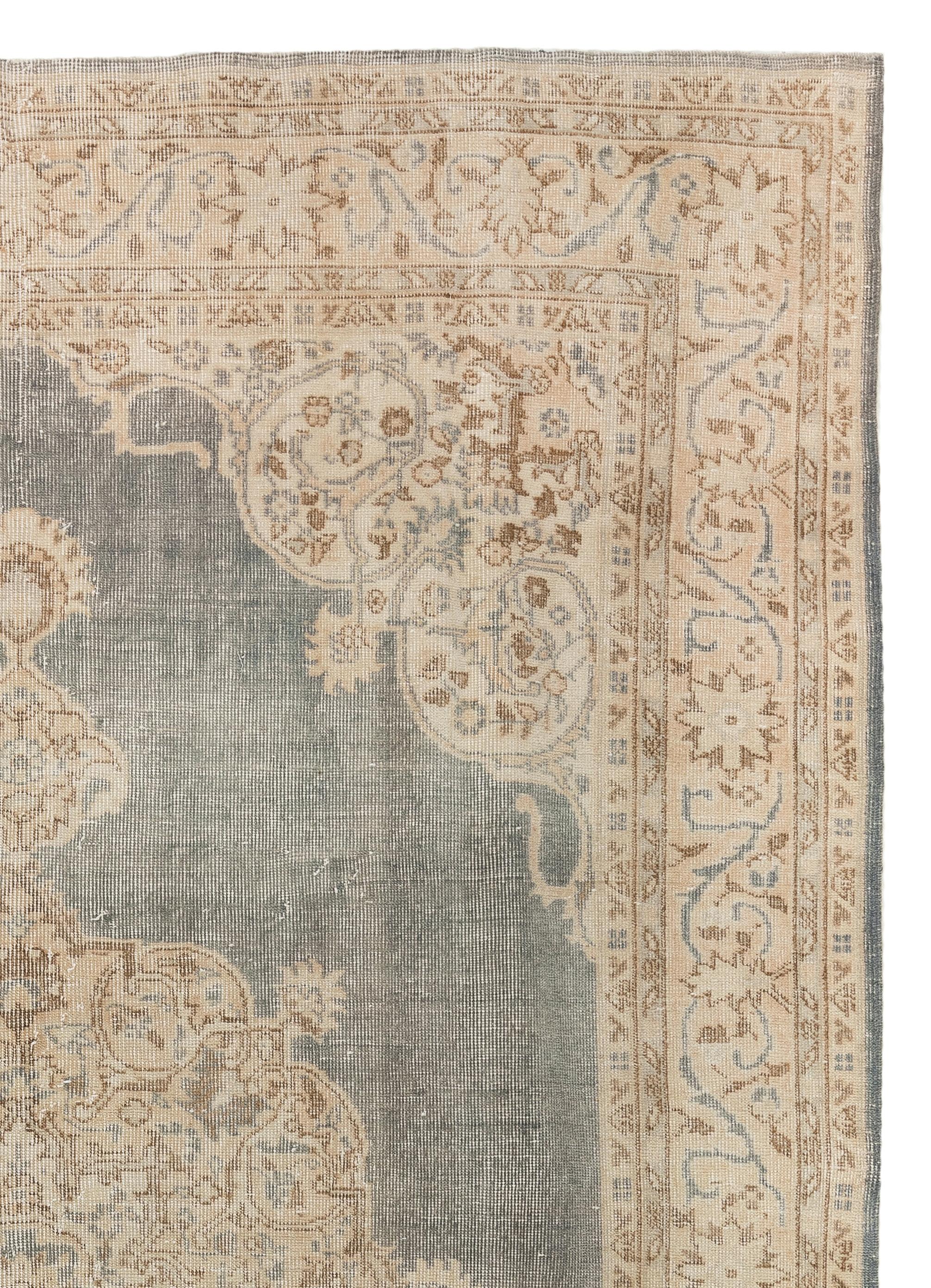 An impressive, hand-knotted Turkish area rug from the 1960s with distressed low wool pile on cotton foundation. It features an intricate, large central medallion in sand/gold color against a slightly greenish gray background. The border and corner