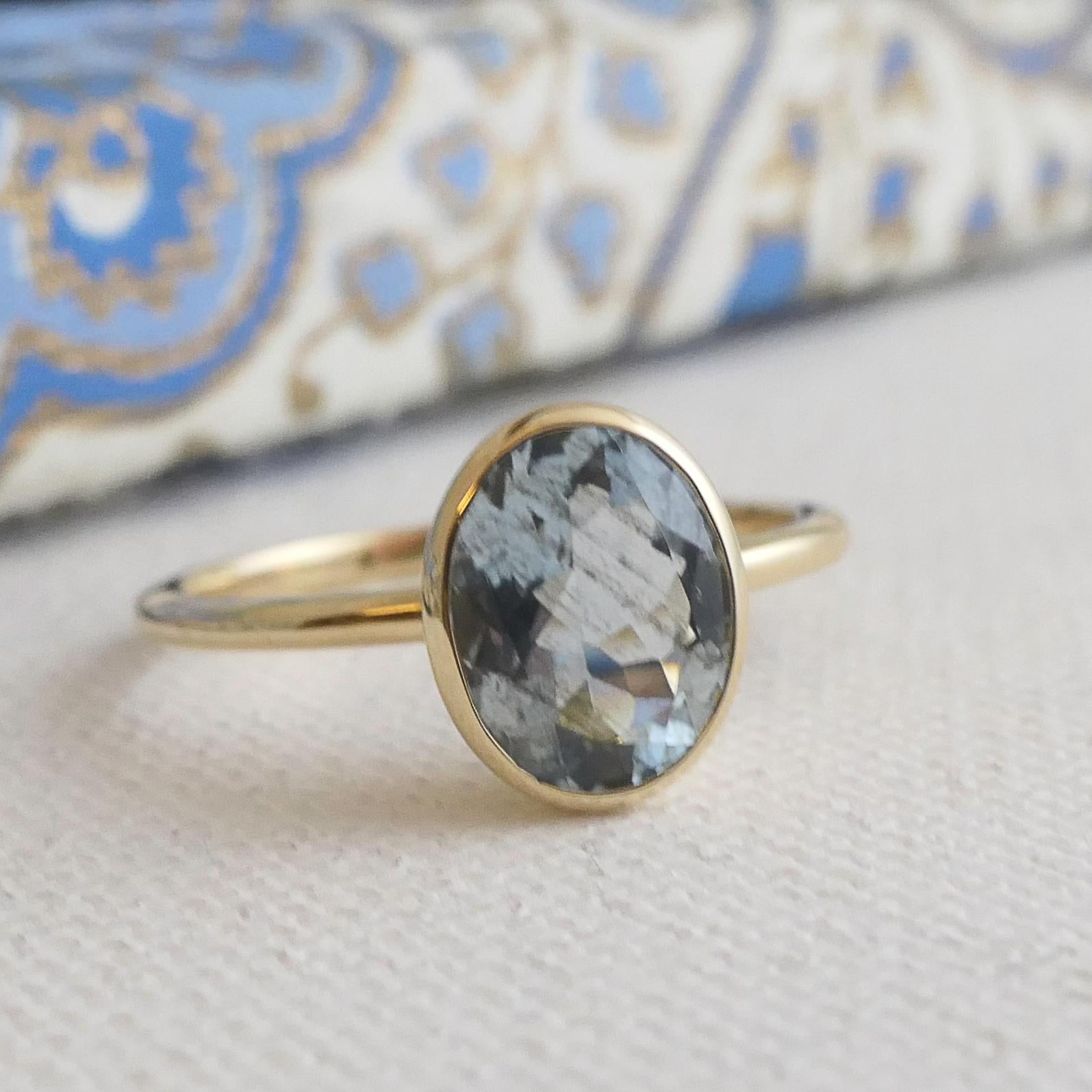 Cette élégante bague est ornée d'une aigue-marine de 7x9 mm sertie dans un élégant chaton en or jaune 14 carats. La teinte bleue pâle et douce de l'aigue-marine contraste magnifiquement avec les tons chauds et dorés, créant un look intemporel et