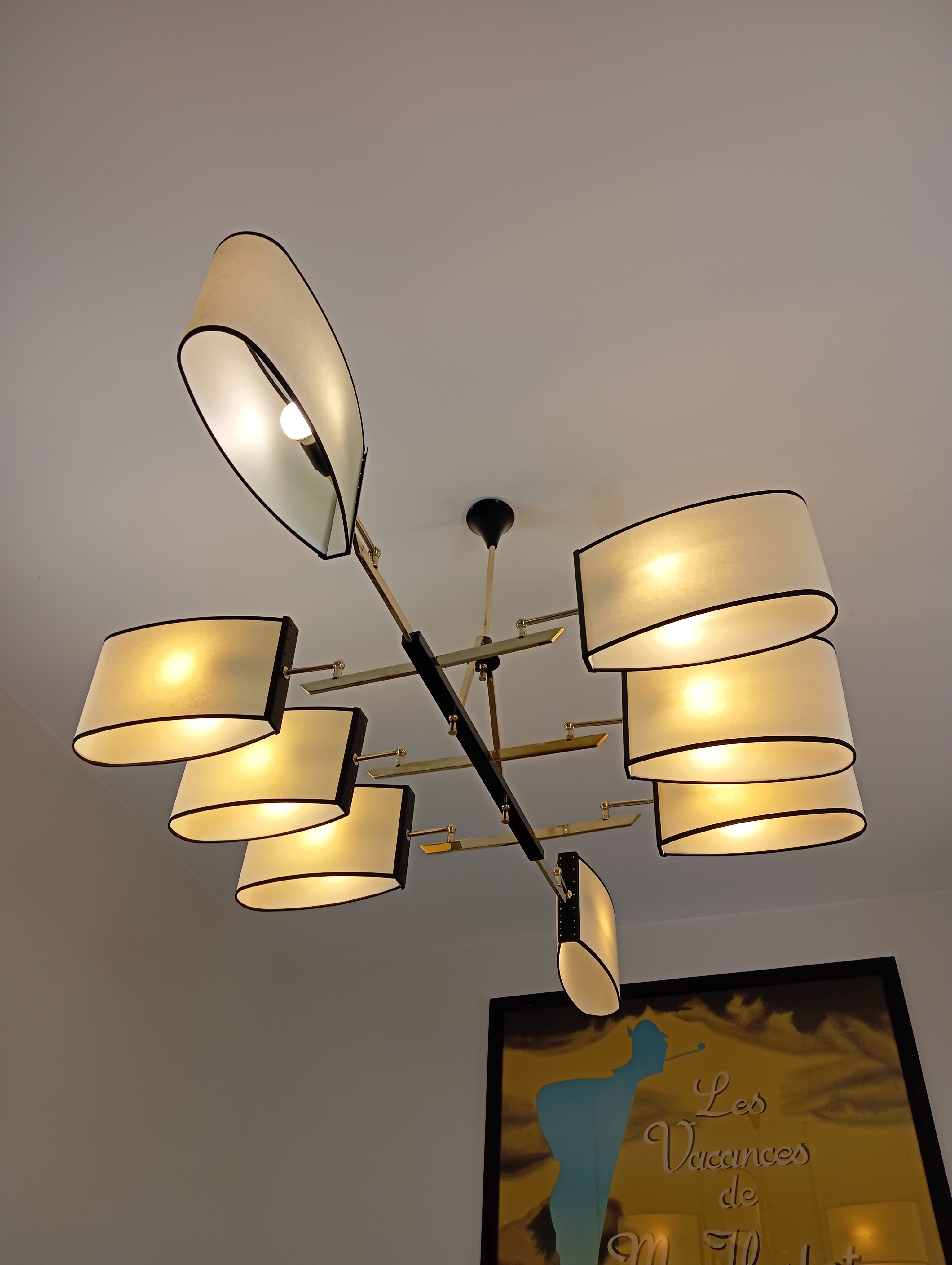 Metal and brass chandelier, consisting of a rectangular base in black lacquered metal, on which are fixed 8 brass light arms, supporting oval-shaped shades.
French work circa 1950,  to Maison Lunel.
The chandelier has been restored, and the height