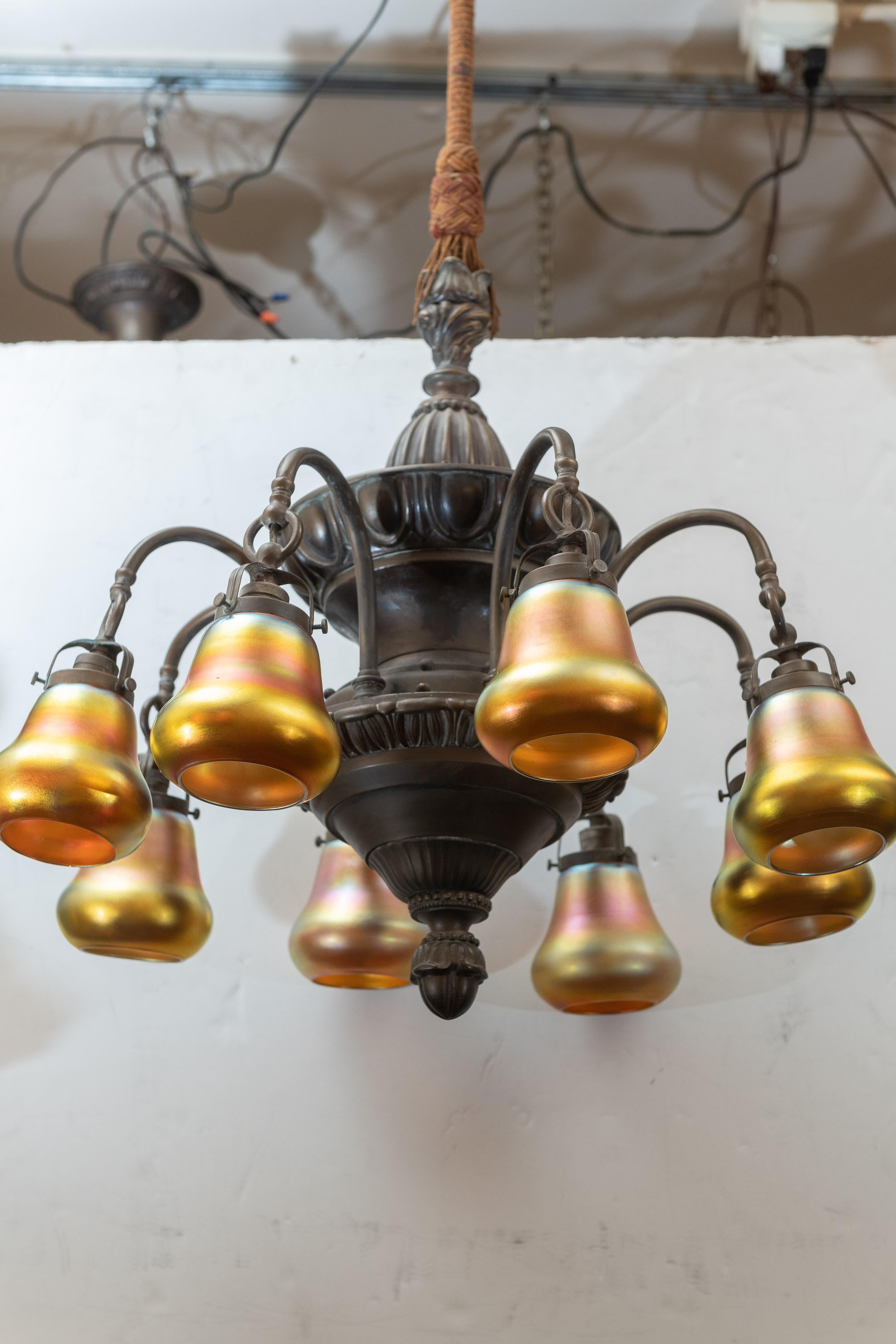 This very handsome chandelier will give you all the light you need with 8-elegant Steuben aurene shades. The body is well constructed and nicely patinated in a soft warm brown. Not easy to find such a fine piece of lighting with so many arms. We