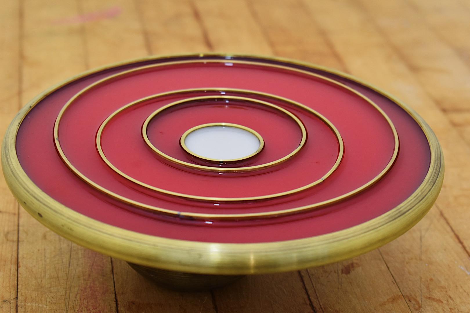 This is a table statement piece!  Modern and colorful, the 8 inch spun brass shell with varying sized brass rings is filled with tinted epoxy.  The rings act as the heat holding trivet element.  Natural brass markings over time appear and spun marks