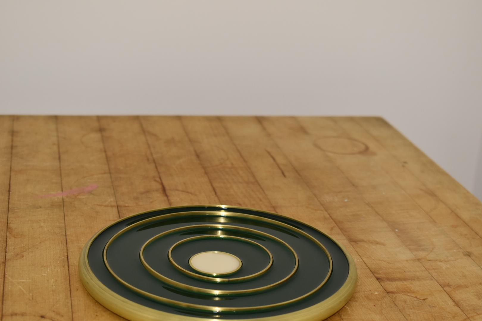 This is a table statement piece!  Modern and colorful, the 8 inch spun brass shell with varying sized brass rings is filled with tinted epoxy.  The rings act as the heat holding trivet element.  Natural brass markings over time appear and spun marks