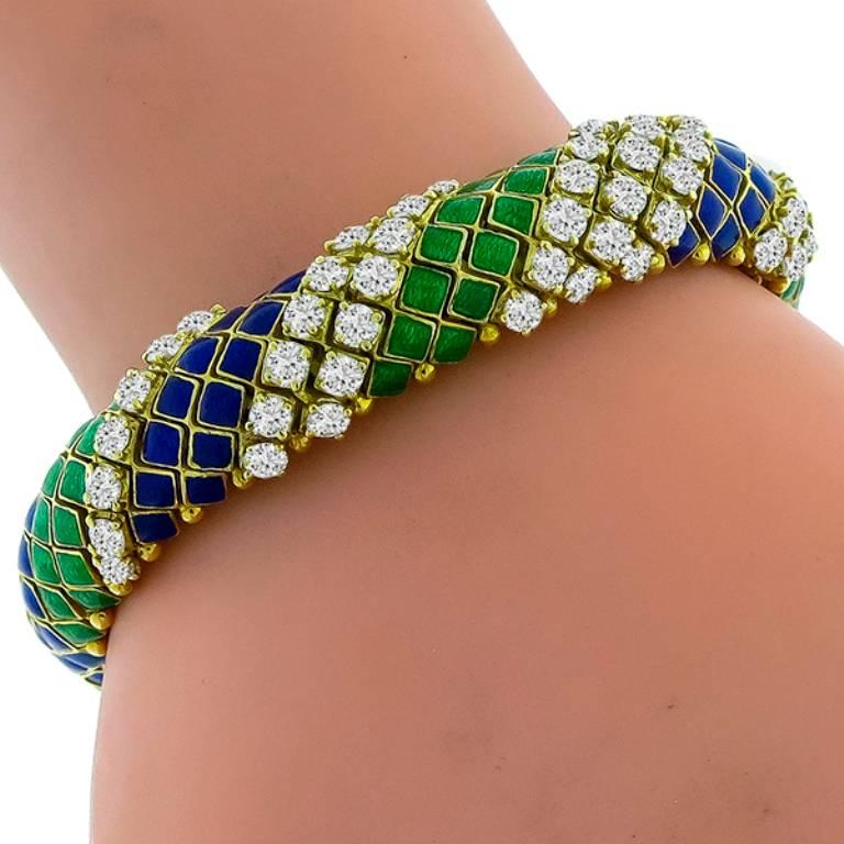 This gorgeous 18k yellow gold bracelet features green and blue enamel inlay, accentuated with high quality sparkling round cut diamonds that weigh approximately 8.00ct. graded G-H color with VS clarity. It measures 7 1/2 inches in length, 12mm in