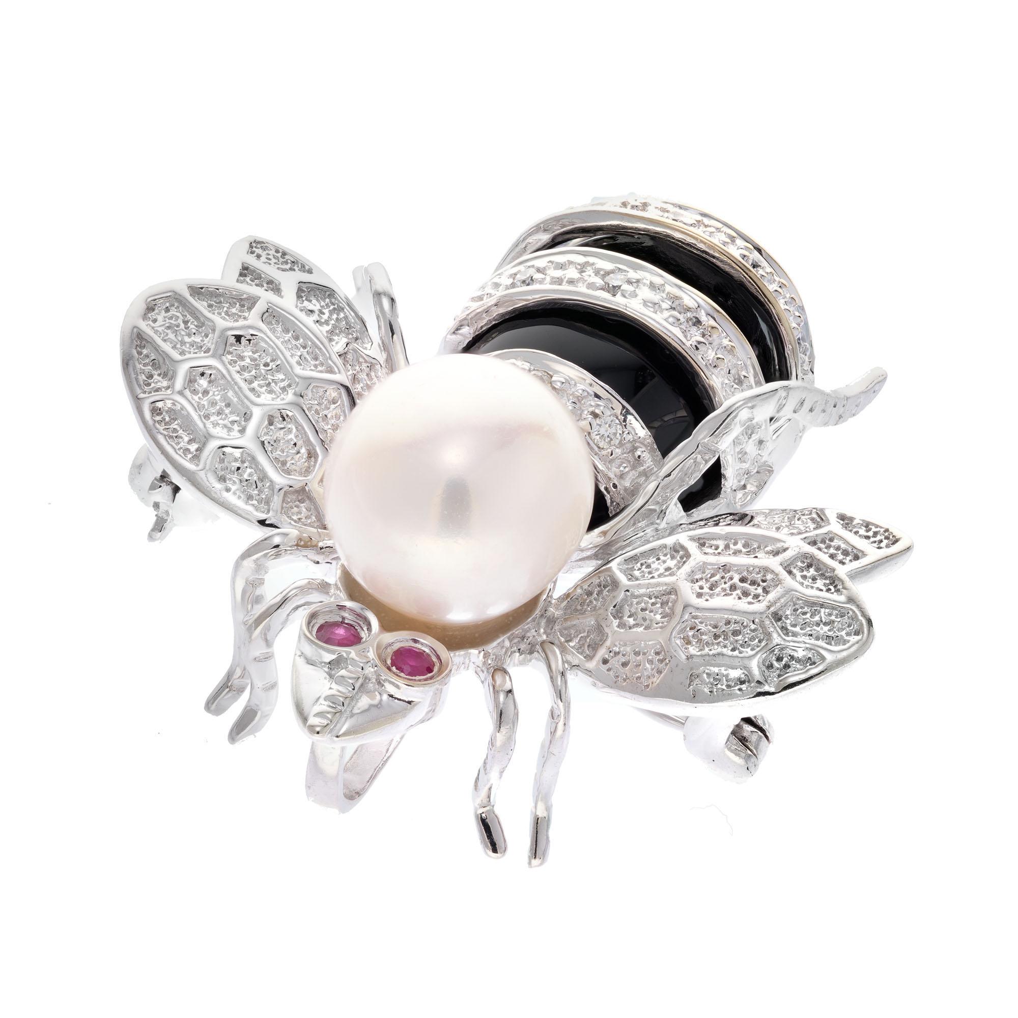 Diamond, ruby and pearl Bee brooch.  14k white gold Bee brooch with ruby eyes, pearl and onyx accents in 14k white gold. There is a loop behind the head for a pendant. 

12 round diamonds, G-H SI approx. .8cts
2 round red rubies, approx. .2cts
1
