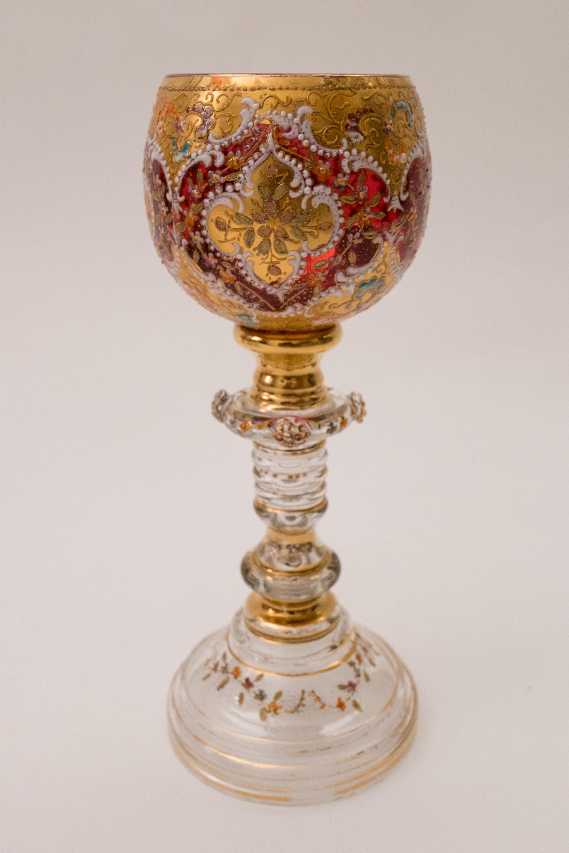 A fantastic set of 8 wine glasses from the storied glass firm of Moser. They have intricate enameling on 24 karat gold on their ruby bowls along with applied prunts to their knob stems and stepped base. Truly incredible craftsmanship. All are in