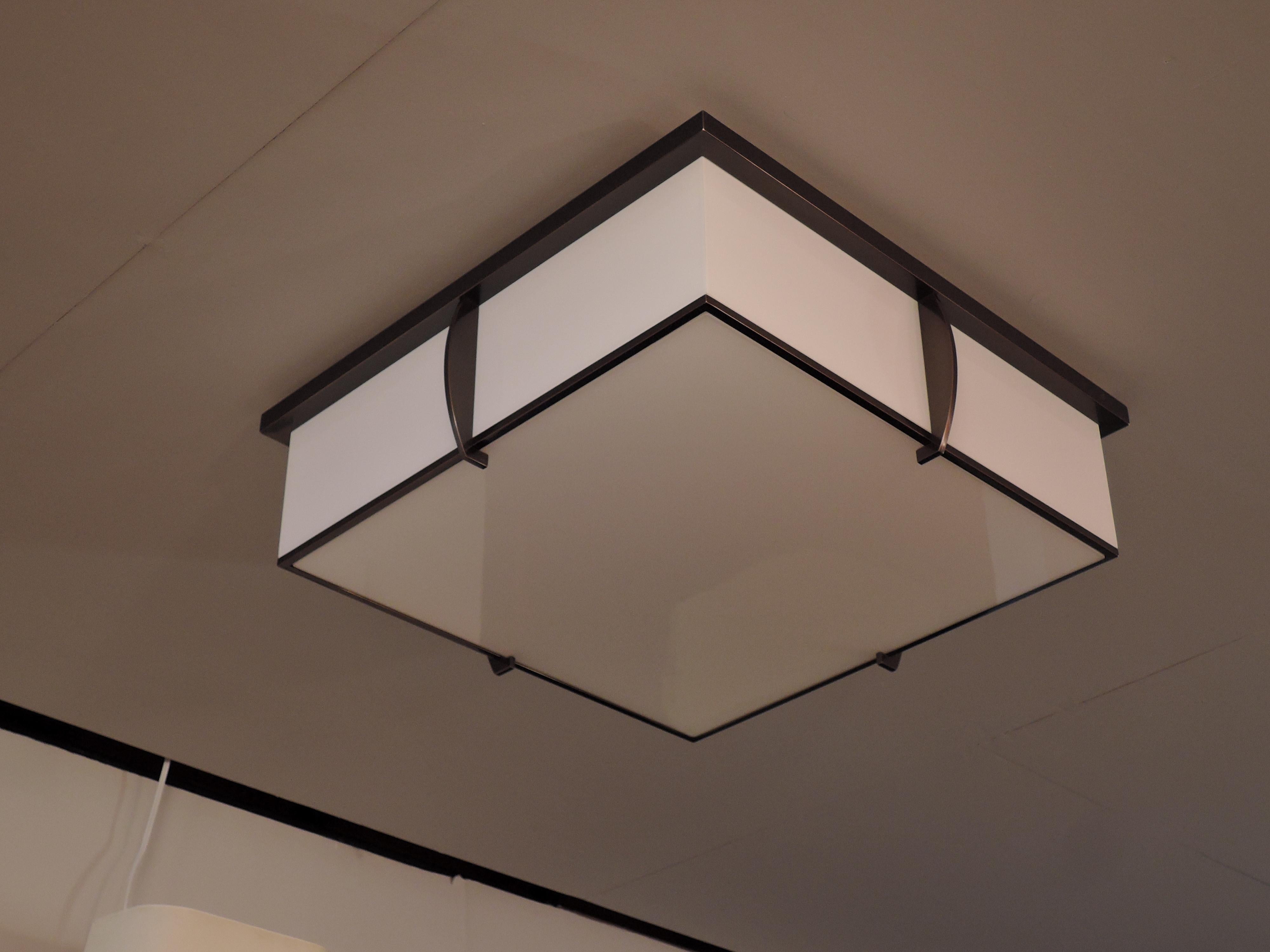 Mounted on a brown patina bronze square frame that holds the white enameled optical glass diffusers.
The flat square horizontal diffuser is easily removable in order to change the bulbs.
Glass diffusers are whiter than they appear on the