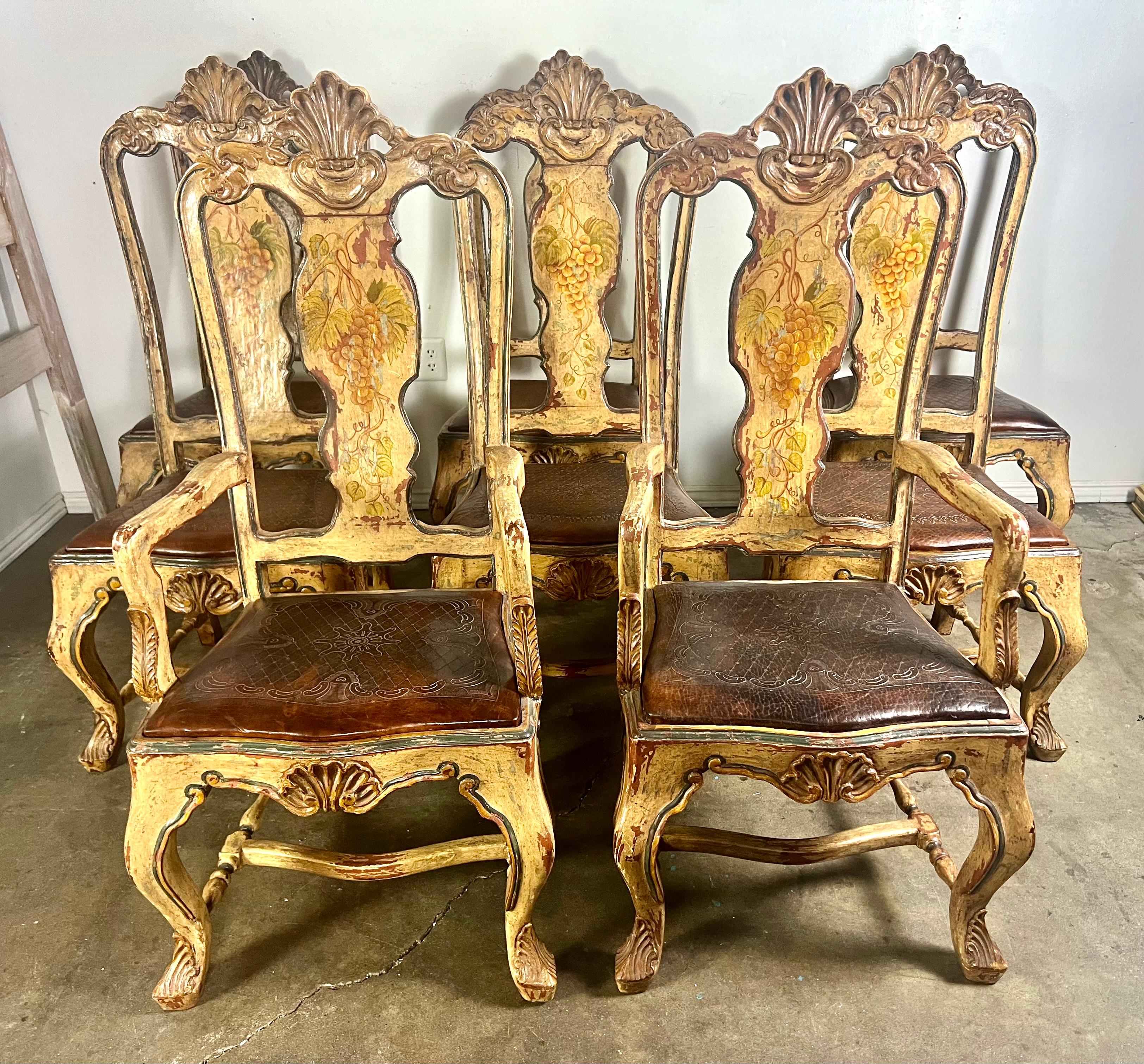 Set of eight hand painted French Provincial style dining chairs with leather embossed seats.  The chairs stand on four cabriole legs with carved feet.  There is a carved shell motif at the top of the backs and on the apron of the chairs.  A bottom