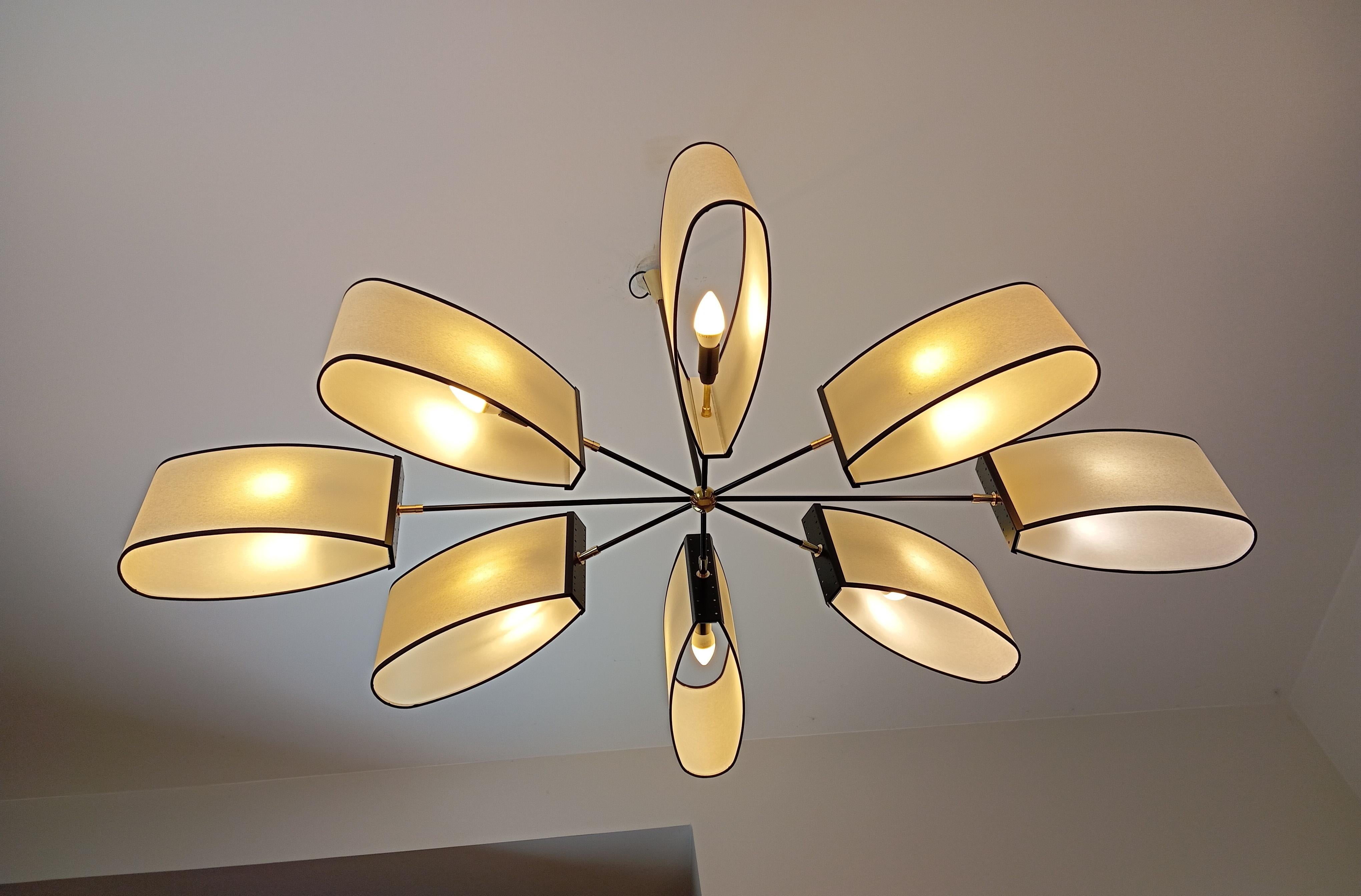 Lustre en laiton et métal laqué noir composé de 8 bras asymétriques terminés par des abat-jours ovales.
Les bras sont reliés par une sphère centrale en laiton.
Travail français circa 1950 par la Maison Lunel.
Ce lustre a été entièrement