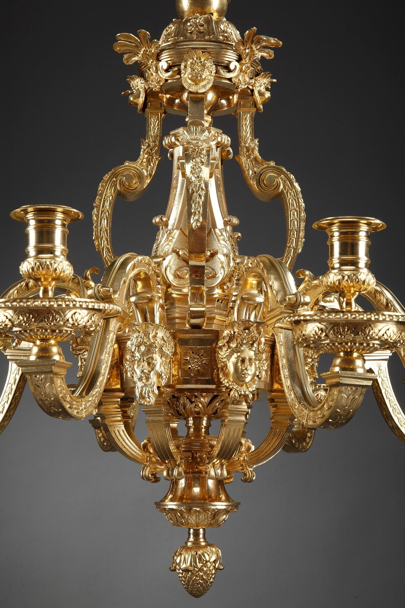 This exquisite ormolu bronze chandelier is crafted in French Regence style. Of opulent design, it bears a rich decoration of scrolls, foliage and putti. This 8-light piece boasts scrolling branches resting upon women and bearded men masks, above