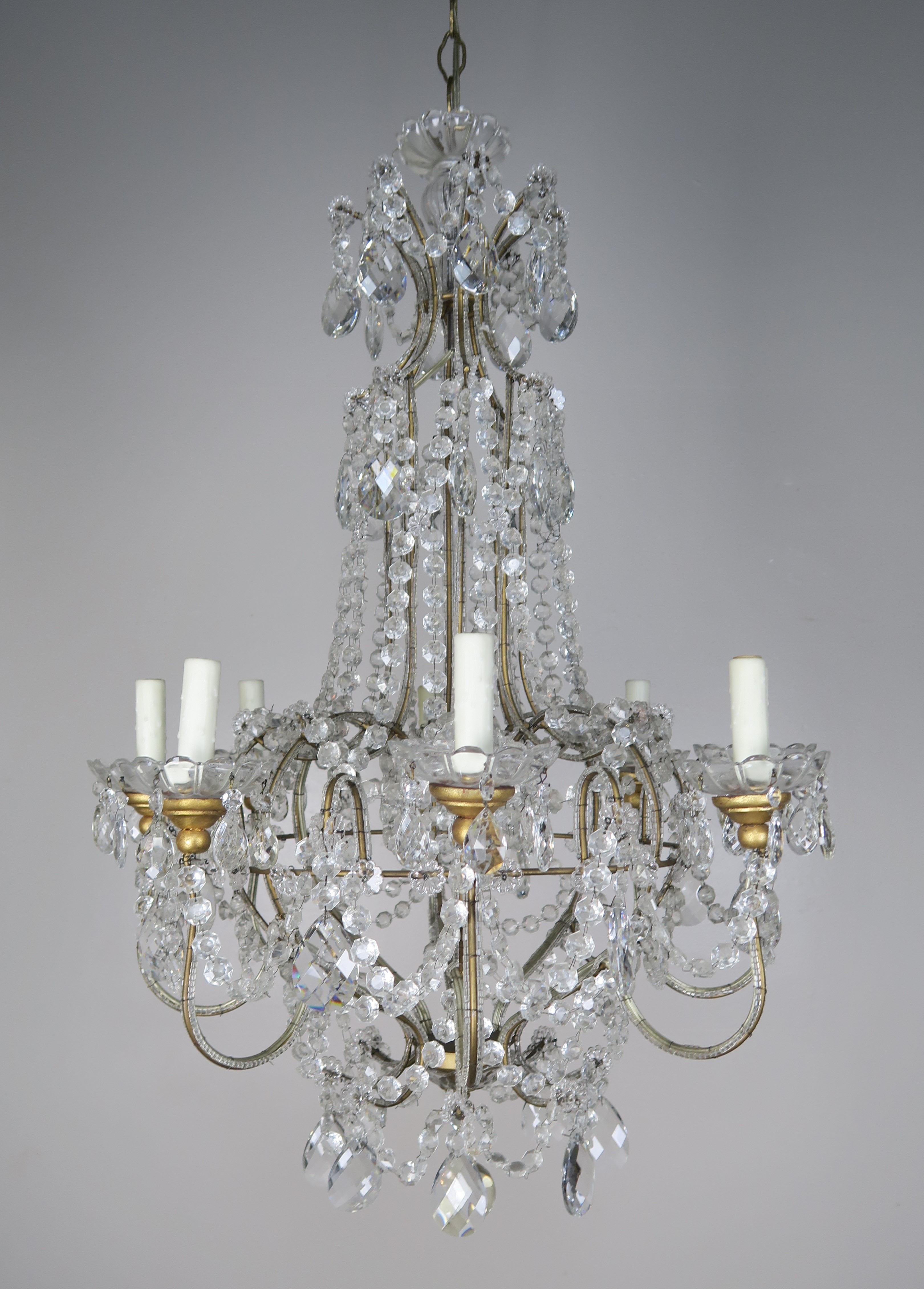 Eight-light crystal beaded arm chandelier adorned with garlands of English cut beads. The garlands of beads drape down into the body of the fixture. Almond shaped faceted crystals can be seen throughout as well. The chandelier has an antique gold