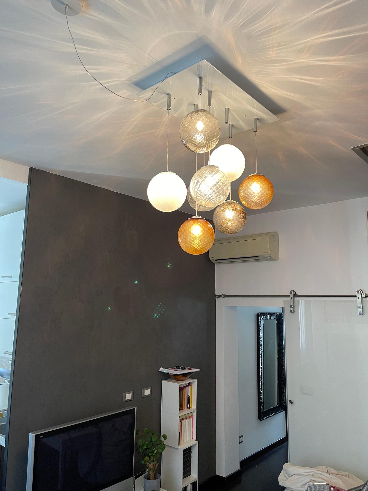 Artistic ceiling chandelier, handcrafted with colored transparent Murano glass spheres. Contemporary, playful, and poetic are some of the adjectives that can be used to describe this chandelier, handmade in our family-owned furnace. This collection