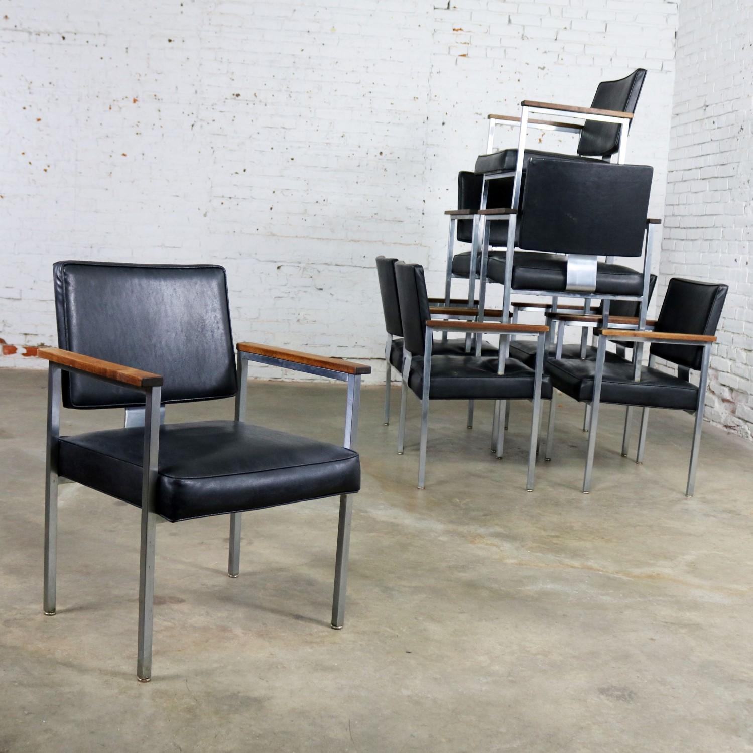 Handsome set of 8 MCM Mid-Century Modern dining or conference room chairs in brushed steel tube and black vinyl upholstery with walnut arms. These chairs were produced by InterRoyal Corp, circa 1970s. They are in fabulous vintage condition with the