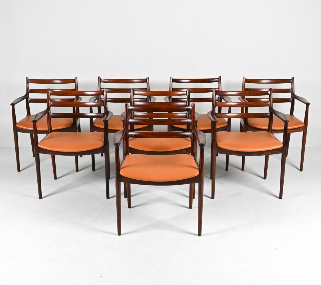 Indulge in the timeless allure of Scandinavian design with this exquisite set of eight dining armchairs, a masterpiece from the esteemed Arne Vodder. Characterized by an elegant ladder-back frame, each chair captures the essence of Mid-Century