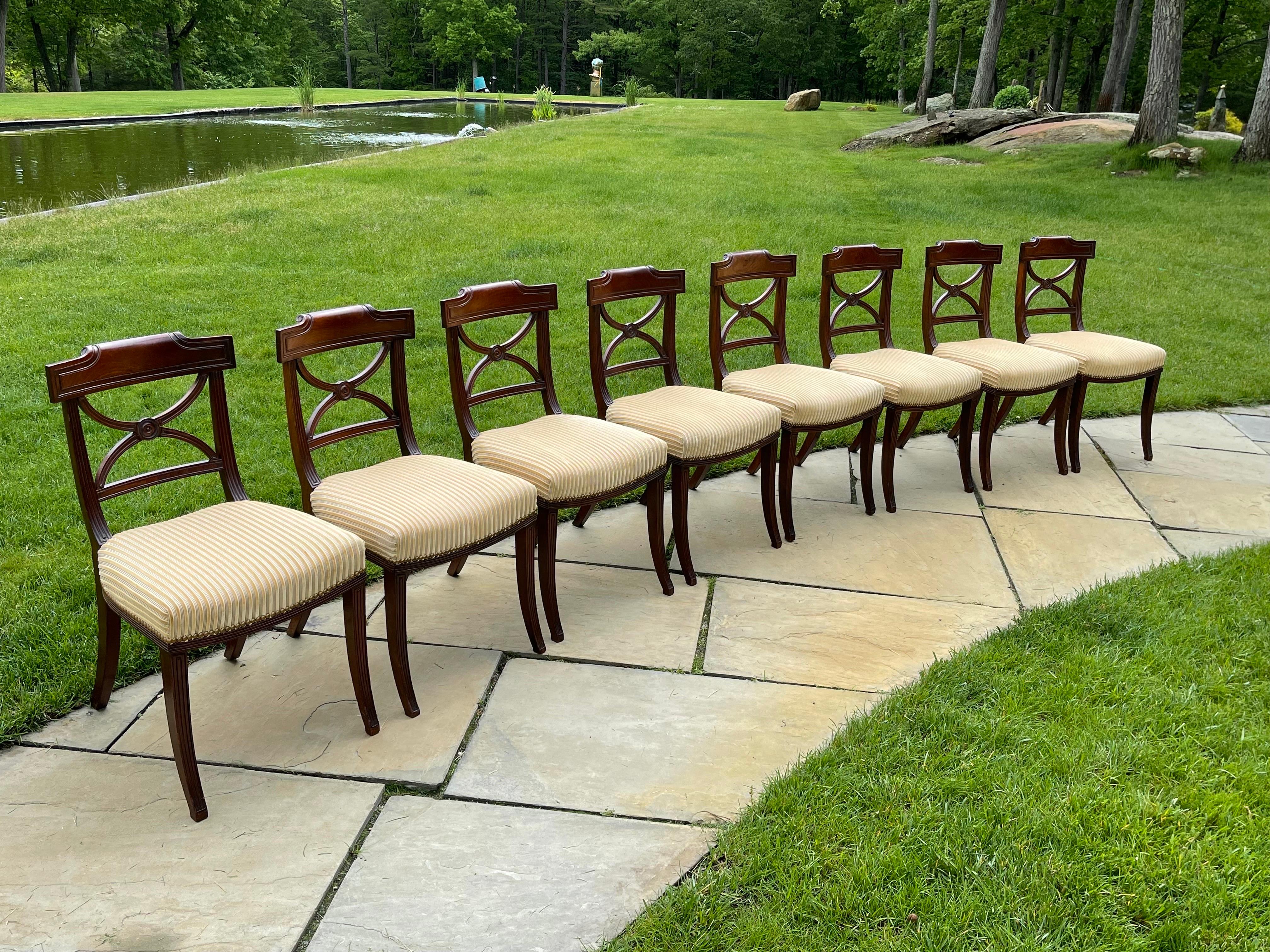 A sophisticated set of 8 Regency Period mahogany dining chairs the Klismos Form, a Gillows Of London Design with a rolled tablet crests and intersecting curved slat backs. 
Made ca 1810-1820 in England. 
The fabric is high quality cotton and