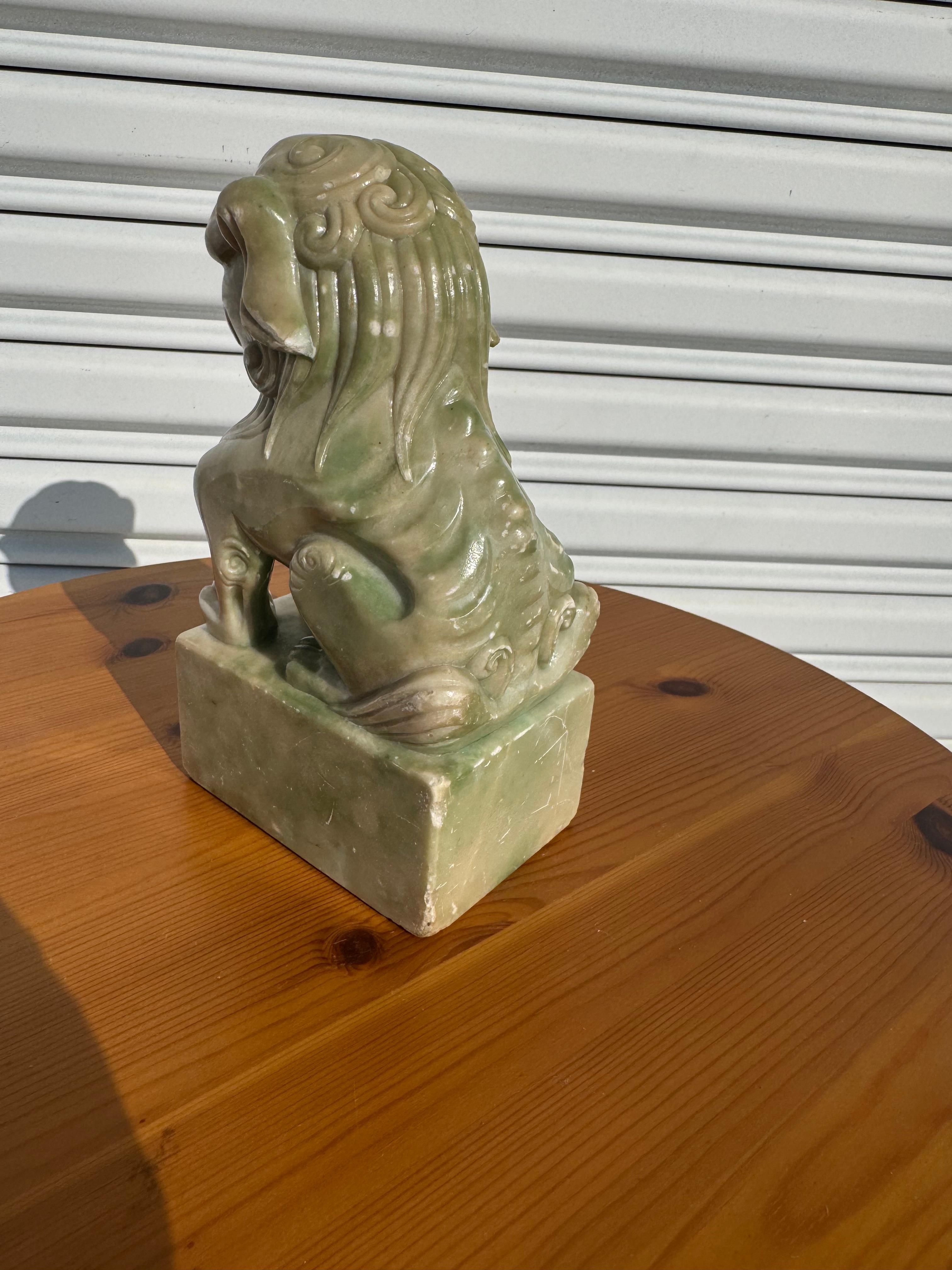 This sculpture is carved from soapstone.
It depicts a Foo Dog mounted on a soapstone base.