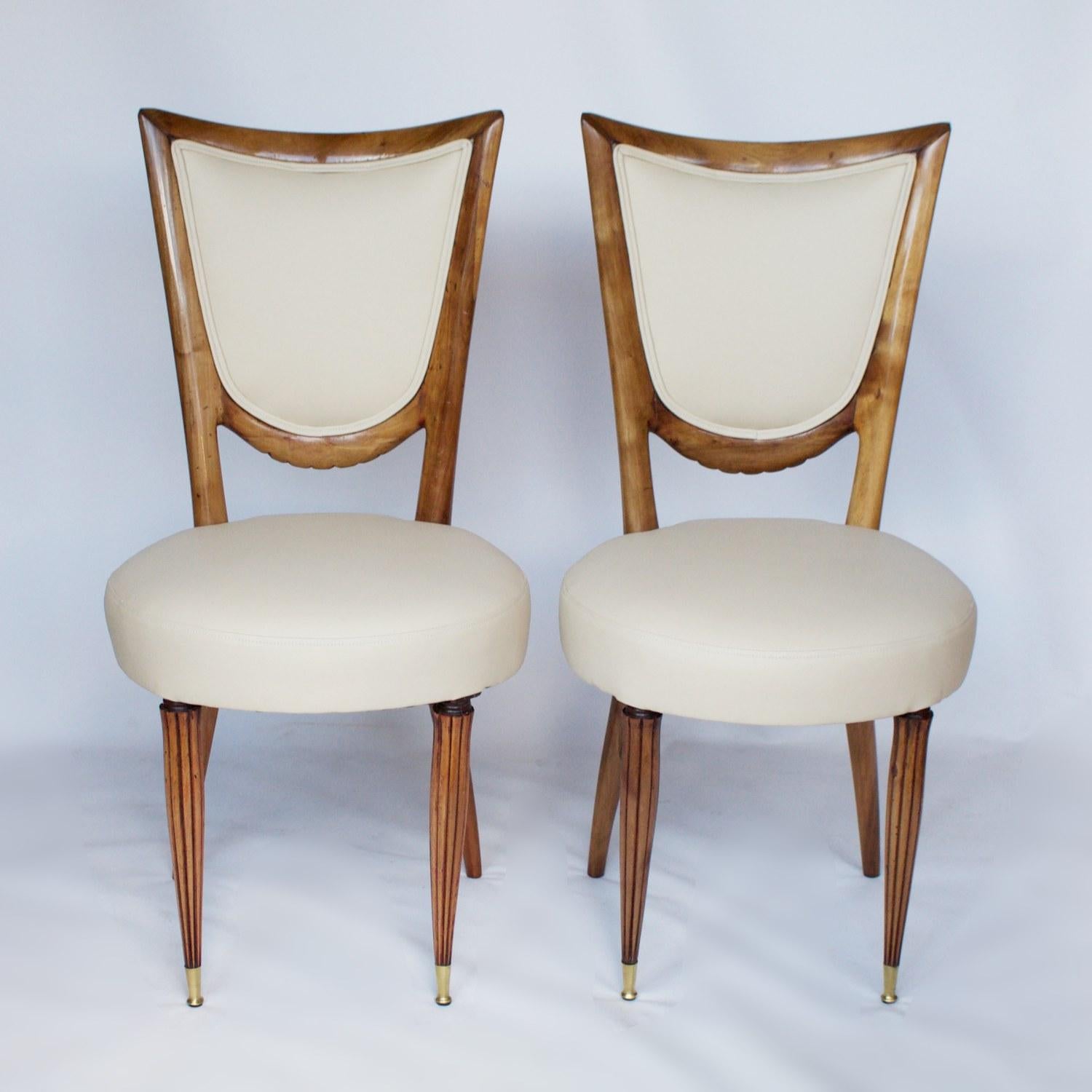 A set of eight Art Deco dining chairs with crescent shaped solid walnut frames, and reeded front legs with their original brass sabot. Re-upholstered in cream leather with oatmeal faux suede to back. 

Dimensions: H 98cm, W 48cm, D 46cm, seat H