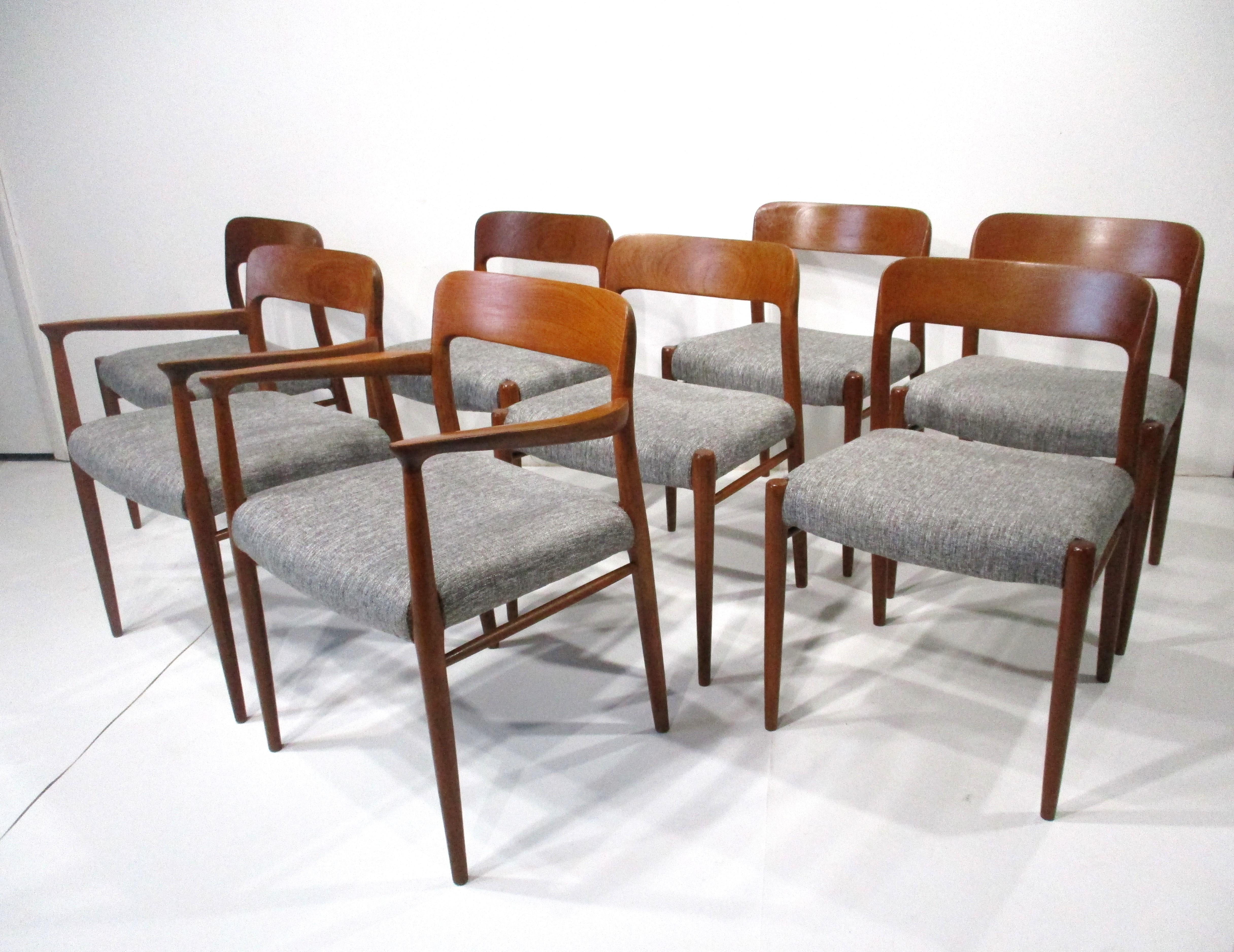 A set of eight sculptural solid teak dining chairs two with arms and six side chairs all with upholstered seats . The seat bottoms are upholstered in a salt  and peppered colored woven contract fabric produced for heavy usage and wear . Designed by