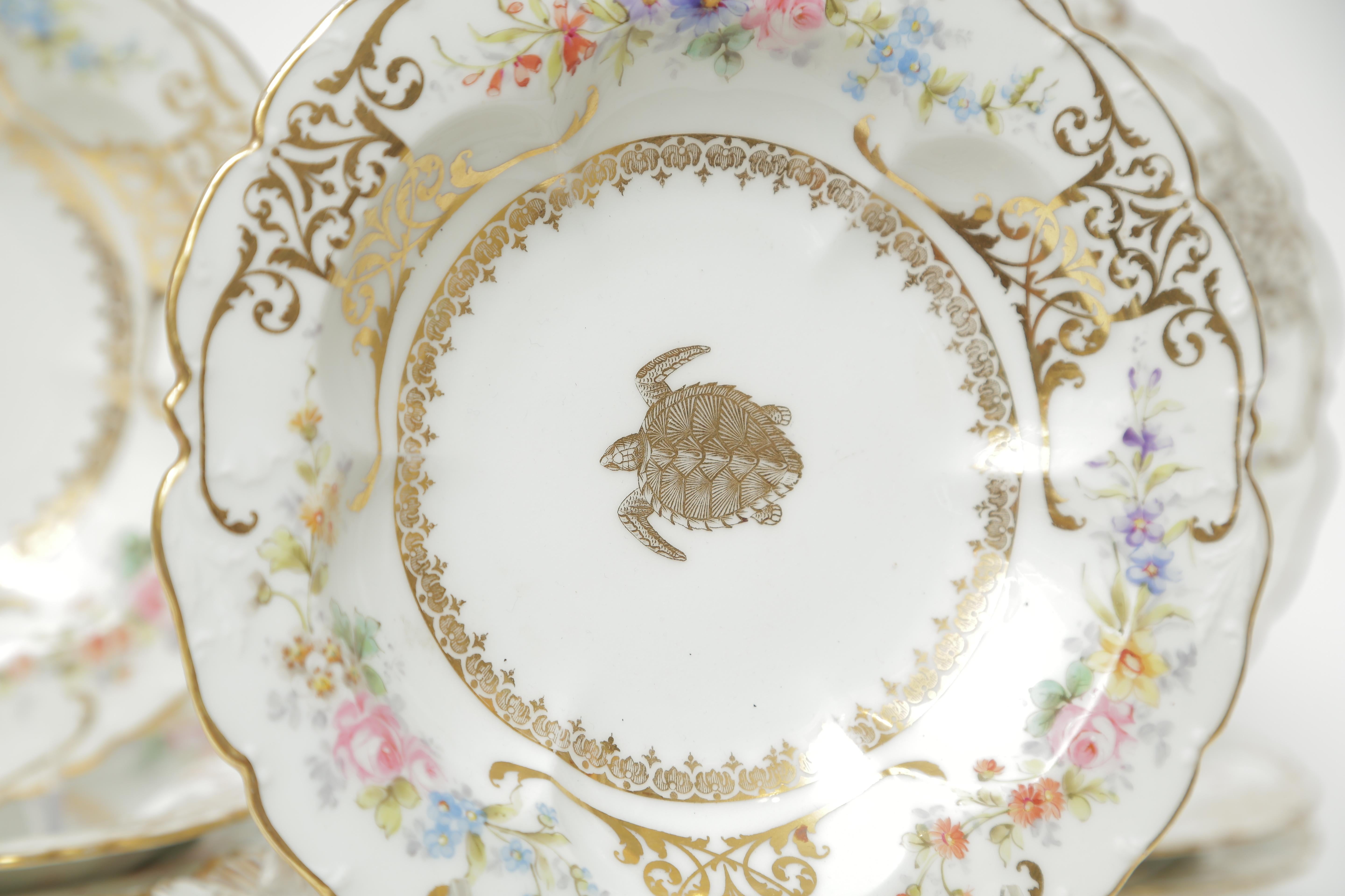 Charming and unique, this set of antique French fine porcelain soup bowls feature hand painted floral cartouches with a central gilt 