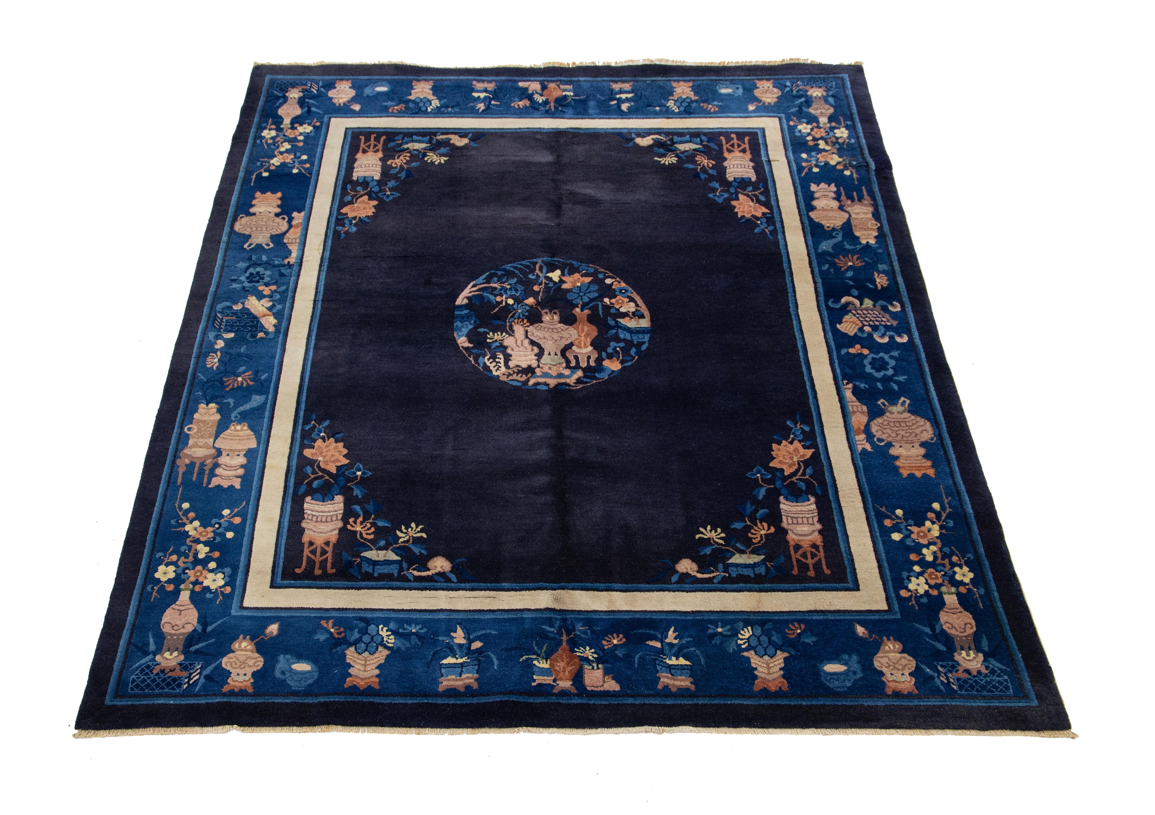 Bellissimo tappeto cinese antico di Pechino, annodato a mano in lana, caratterizzato da un campo blu navy con una cornice marrone e un sottile disegno floreale cinese classico all-over.

Questo tappeto misura: 8' x 9'11