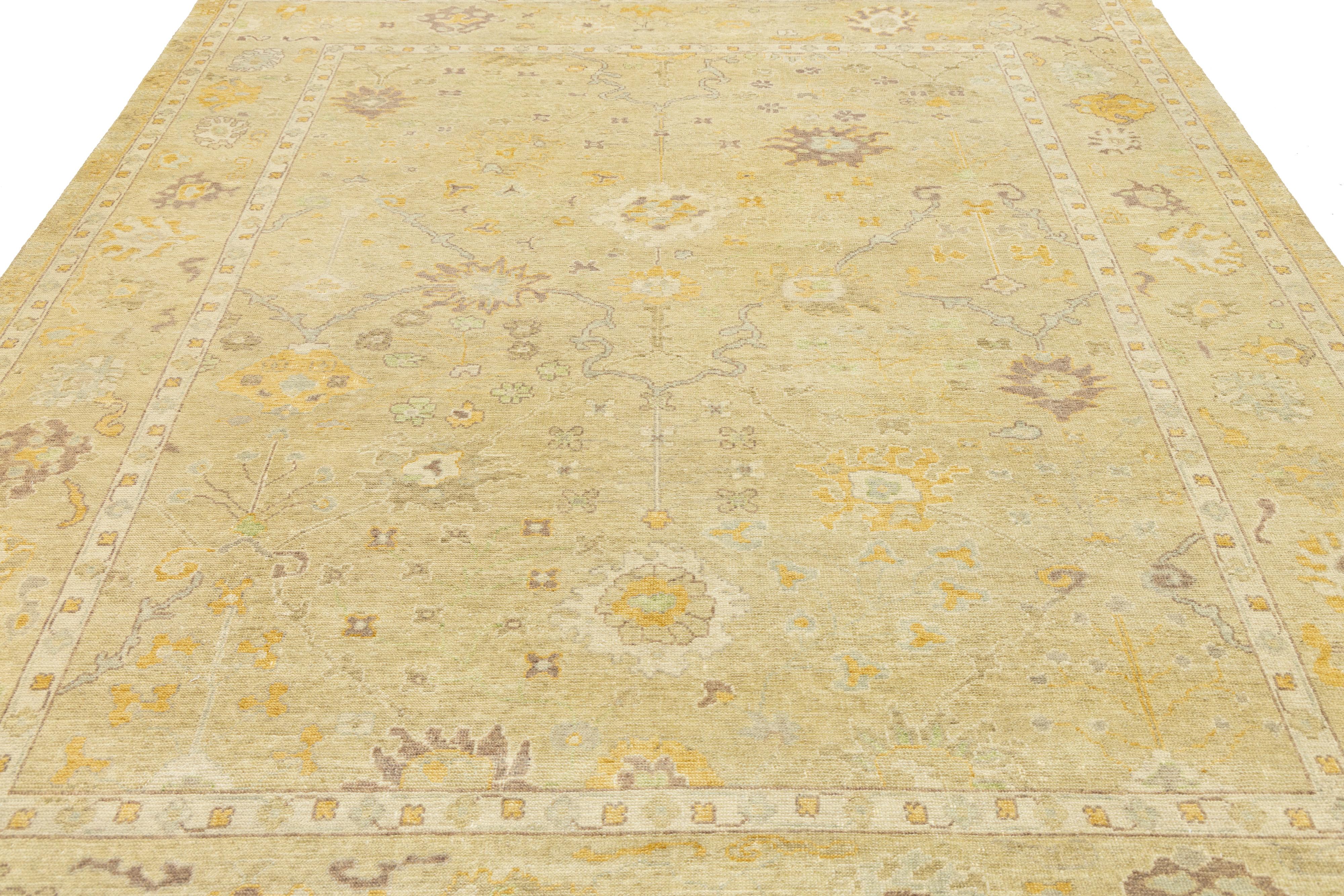 Questo tappeto contemporaneo in lana in stile Oushak combina un design moderno con una lavorazione tradizionale. Ha un sorprendente sfondo marrone ornato da motivi floreali in una sottile gamma di colori, che esaltano la bellezza di qualsiasi