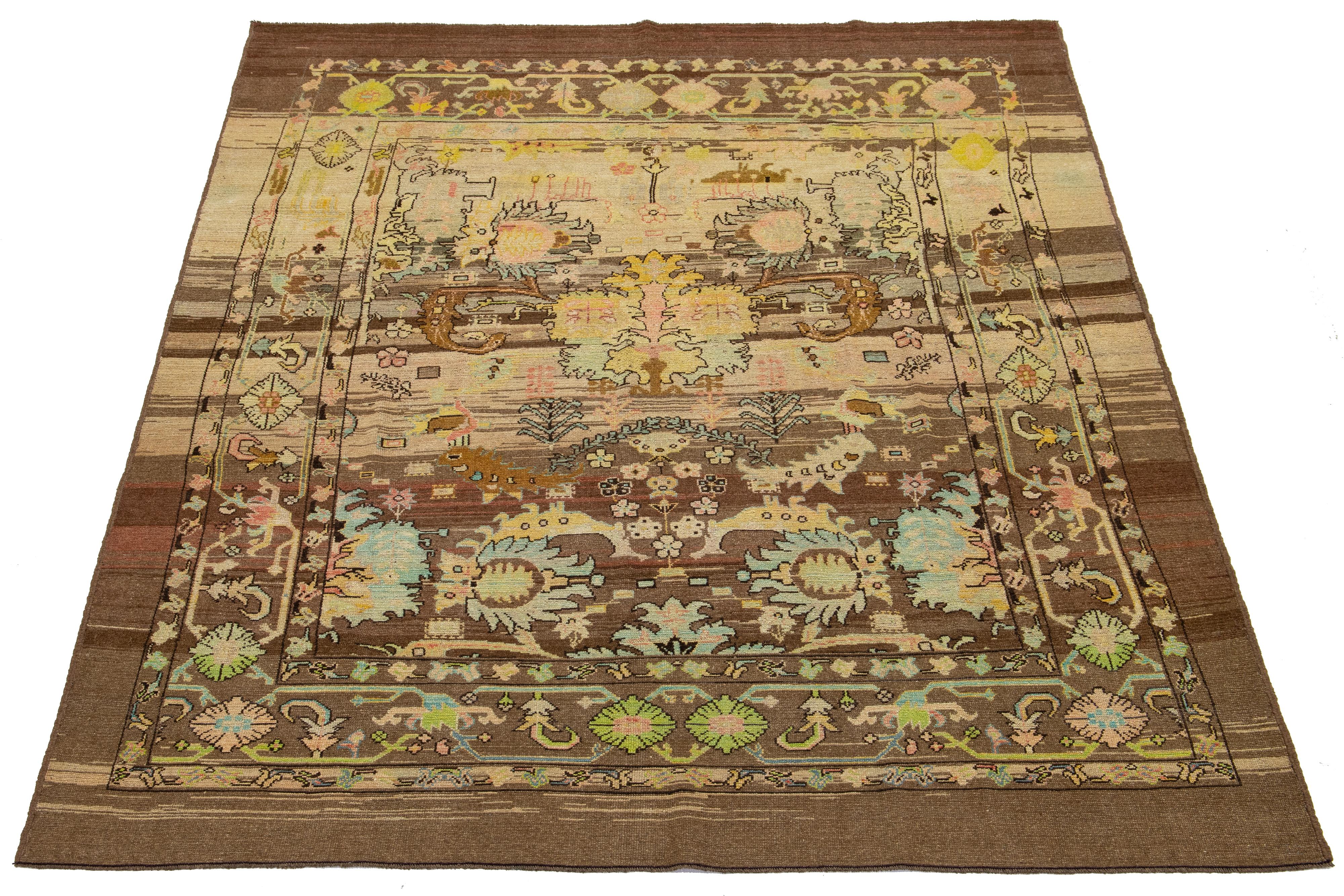 This hand-knotted wool rug, with a brown and beige base, is part of the Apadana Revival Collection. Its striking botanical floral design is enhanced by a blend of teal, peach, green, and yellow accents.

This rug measures 7'11
