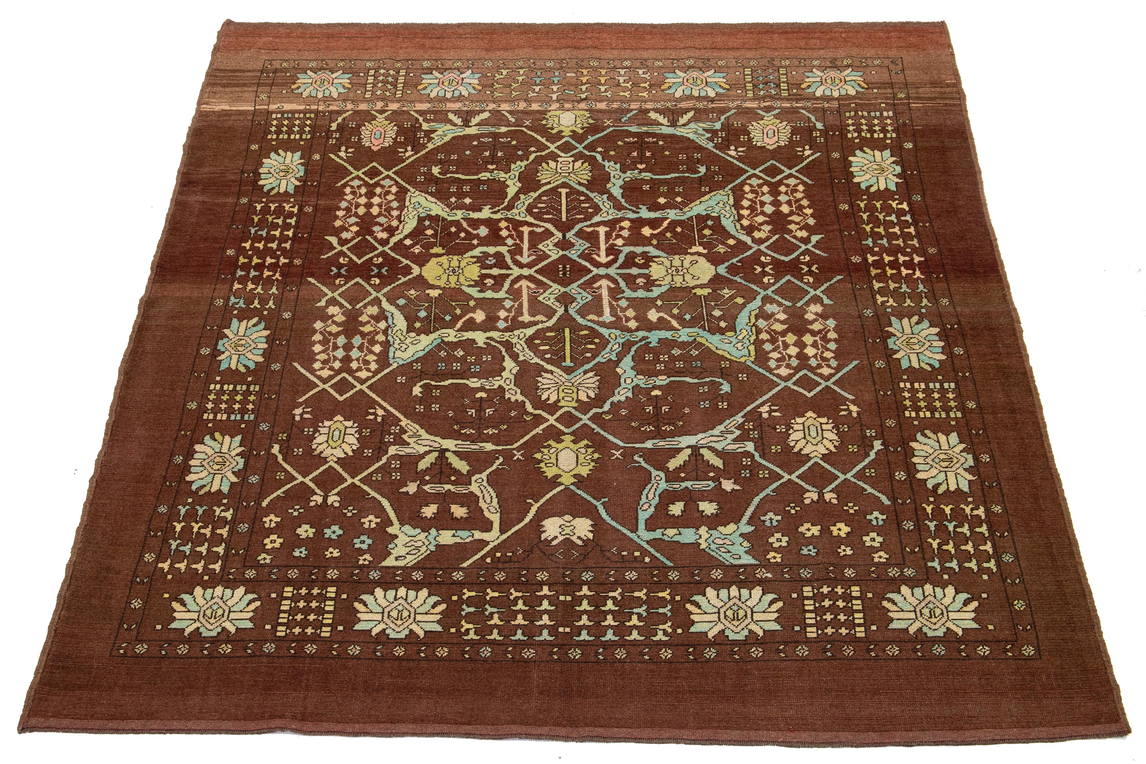 This beautiful, room-sized modern rug is hand-knotted from wool and features a brown and red base. It is part of Apadana's Revival Collection and includes blue, beige, and yellow accents alongside a stunning botanical floral design.

This rug