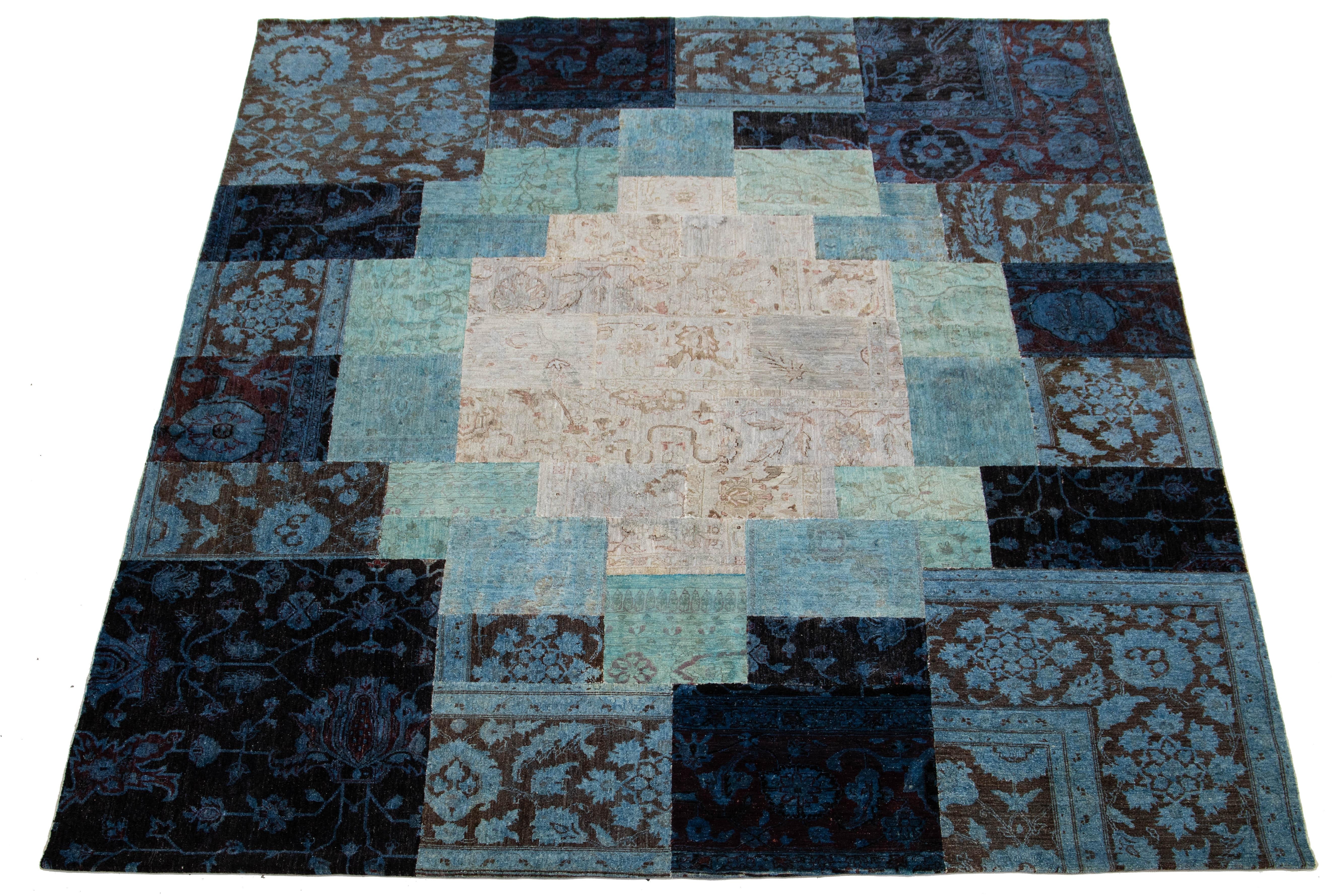Ein atemberaubender, handgefertigter, moderner Wollteppich mit einem fesselnden blauen Feld. Dieses Stück ist mit einem floral inspirierten Muster verziert und verfügt über lebhafte Akzente in Erdtönen, die alle wunderschön in einem Patchwork-Design