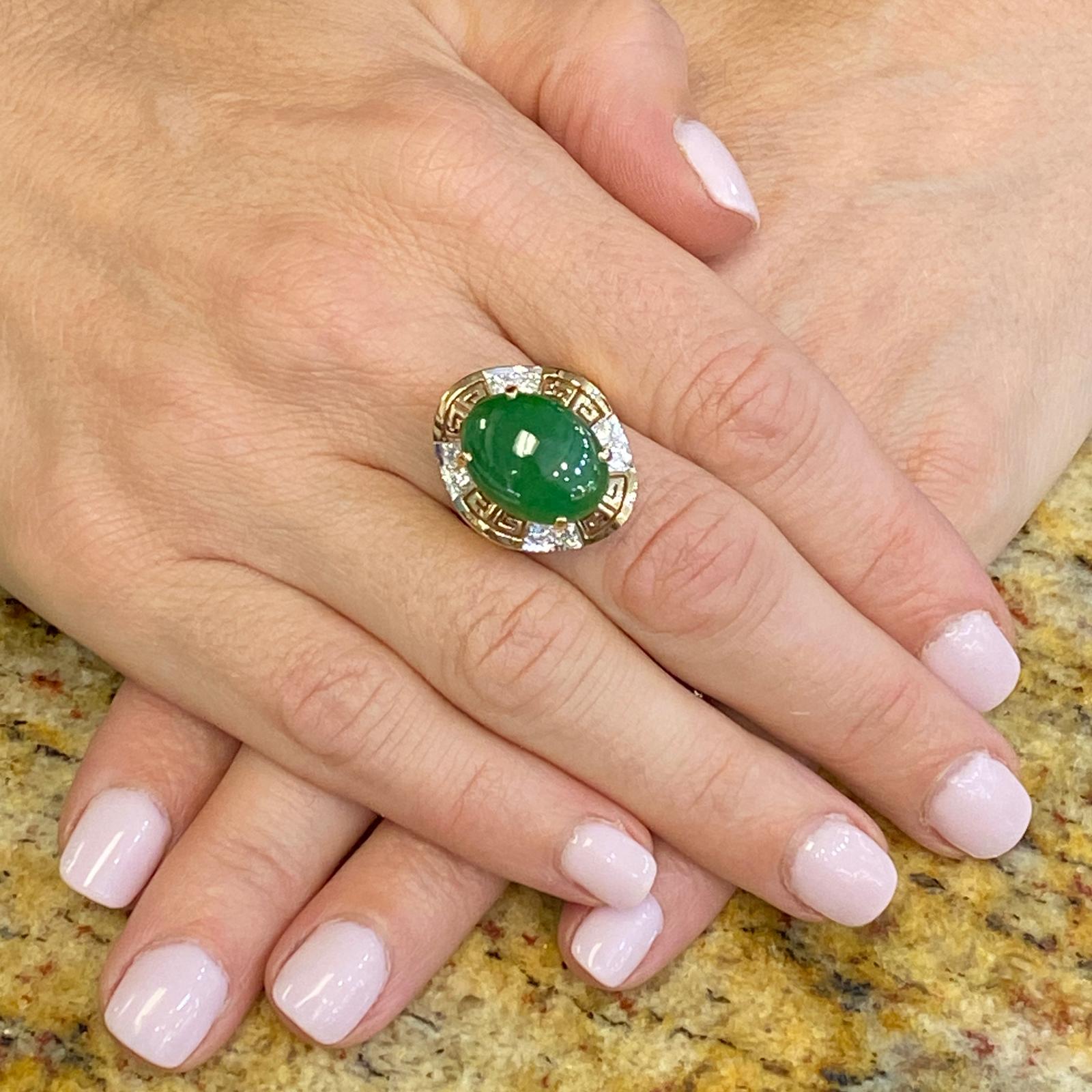 Jade and diamond cocktail ring fashioned in 14 karat yellow gold. The ring features an approximately 8.0 carat cabochon natural jade gemstone with a rich green color. The jade is accented with 8 round brilliant cut diamonds weighing approximately