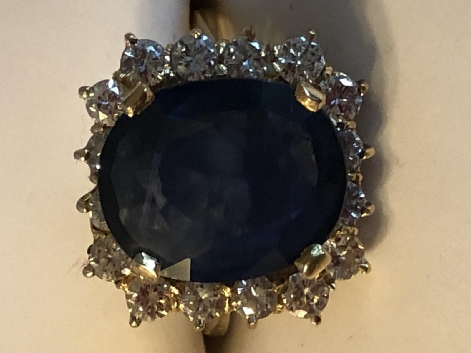 Impressive 14K Yellow Gold with an oval cut Sapphire weighing approximately 8 carats. Prong set with 16 Diamonds weighing approximately 0.08 CTW. Ring size is 7.25. Total weight is 6.8 grams.