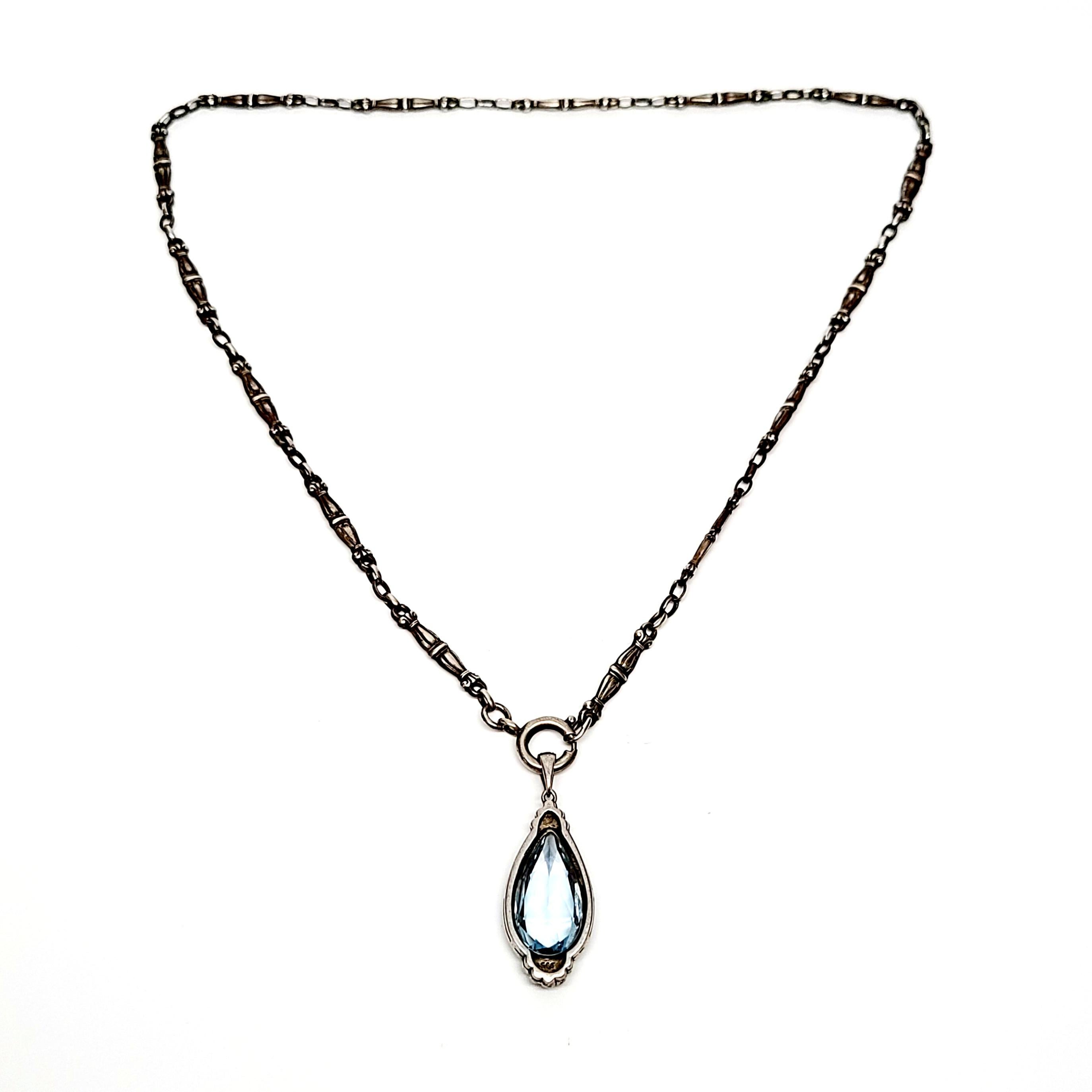 935 silver aquamarine pendant on 800 silver bookchain necklace.

A teardrop aquamarine stone is set in an ornate frame that hangs from a bookchain necklace. Links have a double sided design.

Chain measures approx 18 1/2