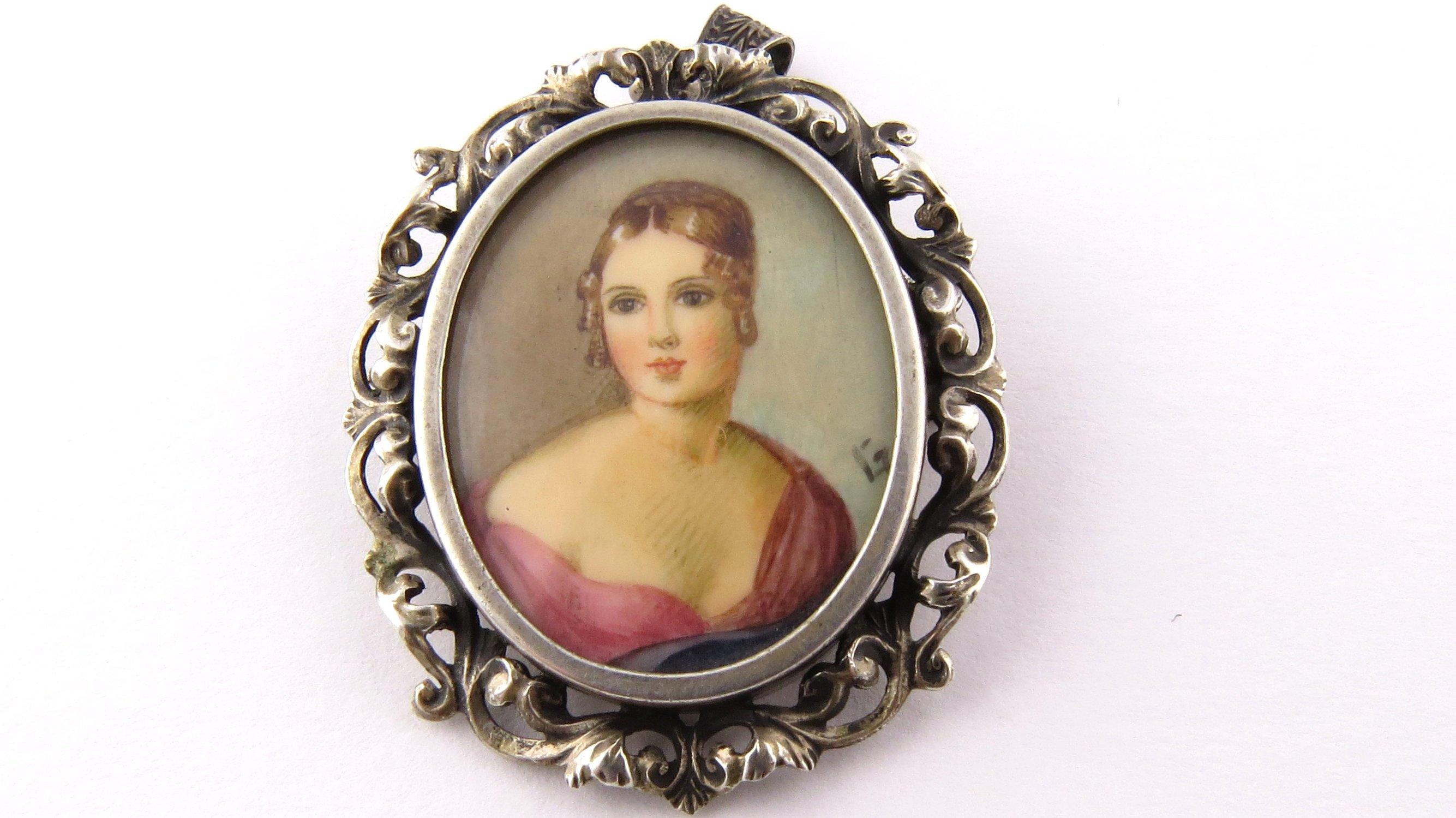 Vintage 800 Silver Hand Painted Portrait Brooch/Pendant- 
This lovely hand painted portrait features a lovely lady framed in ornate 800 silver and covered with glass. Can be worn as a brooch or a pendant. 
Size: 36 mm x 30 mm 
Weight: 4.4 dwt. / 6.9
