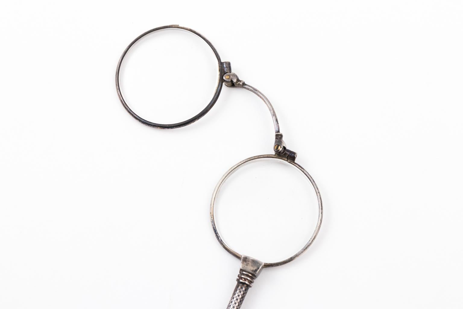 Circa late 19th century 800 Silver lorgnette on an 800 Silver chain. When you pull down the slide on the Lorgnette, the glasses open. The Lorgnette measures 6.50 Inches long. The chain is 30 Inches total. The chain is 2.50 Millimeters wide, the