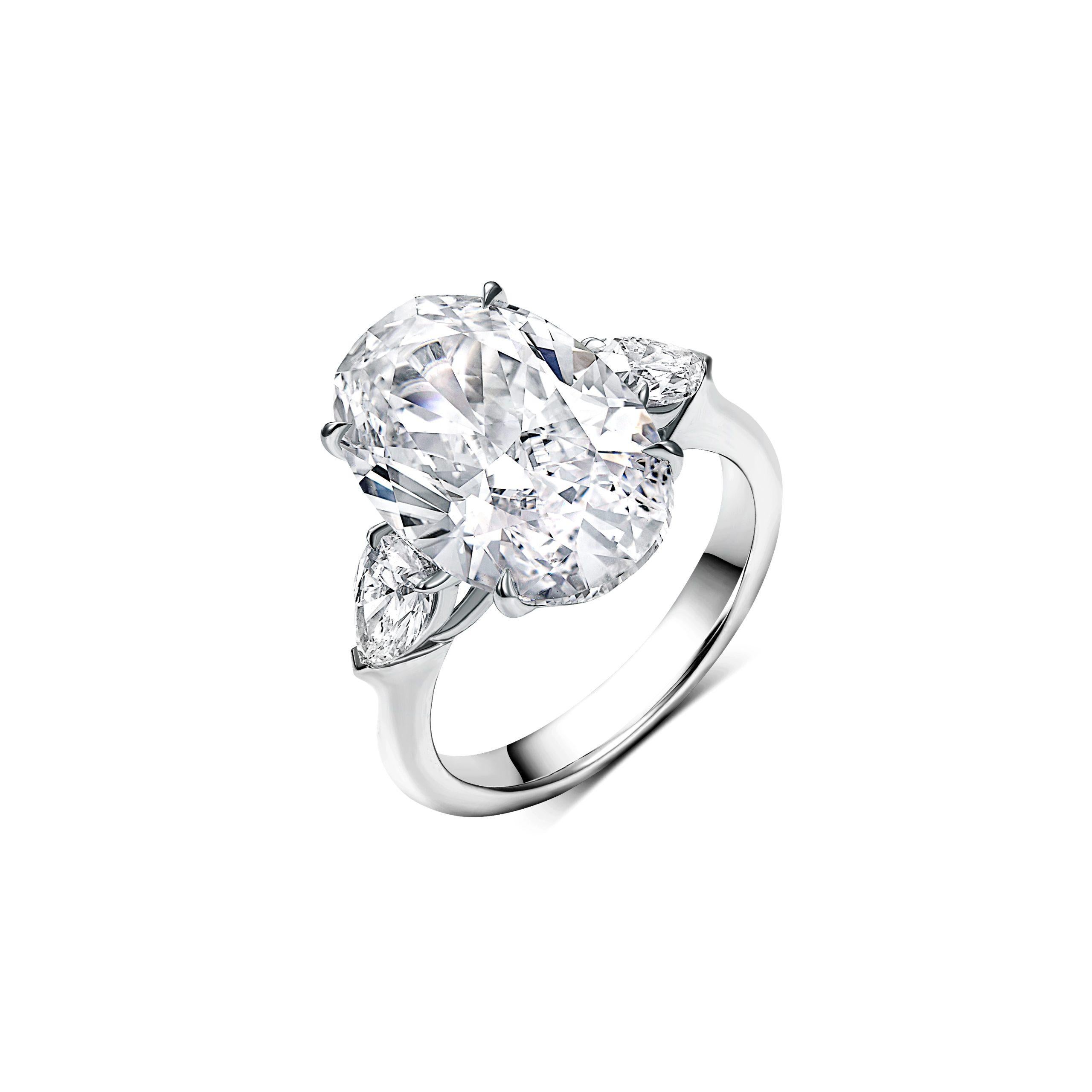 Extraordinaire déclaration d'élégance raffinée, ce diamant ovale brillant de 8,00 carats, certifié GIA, est serti dans un design sophistiqué à trois pierres en platine. La remarquable pierre centrale est flanquée de deux diamants en forme de poire