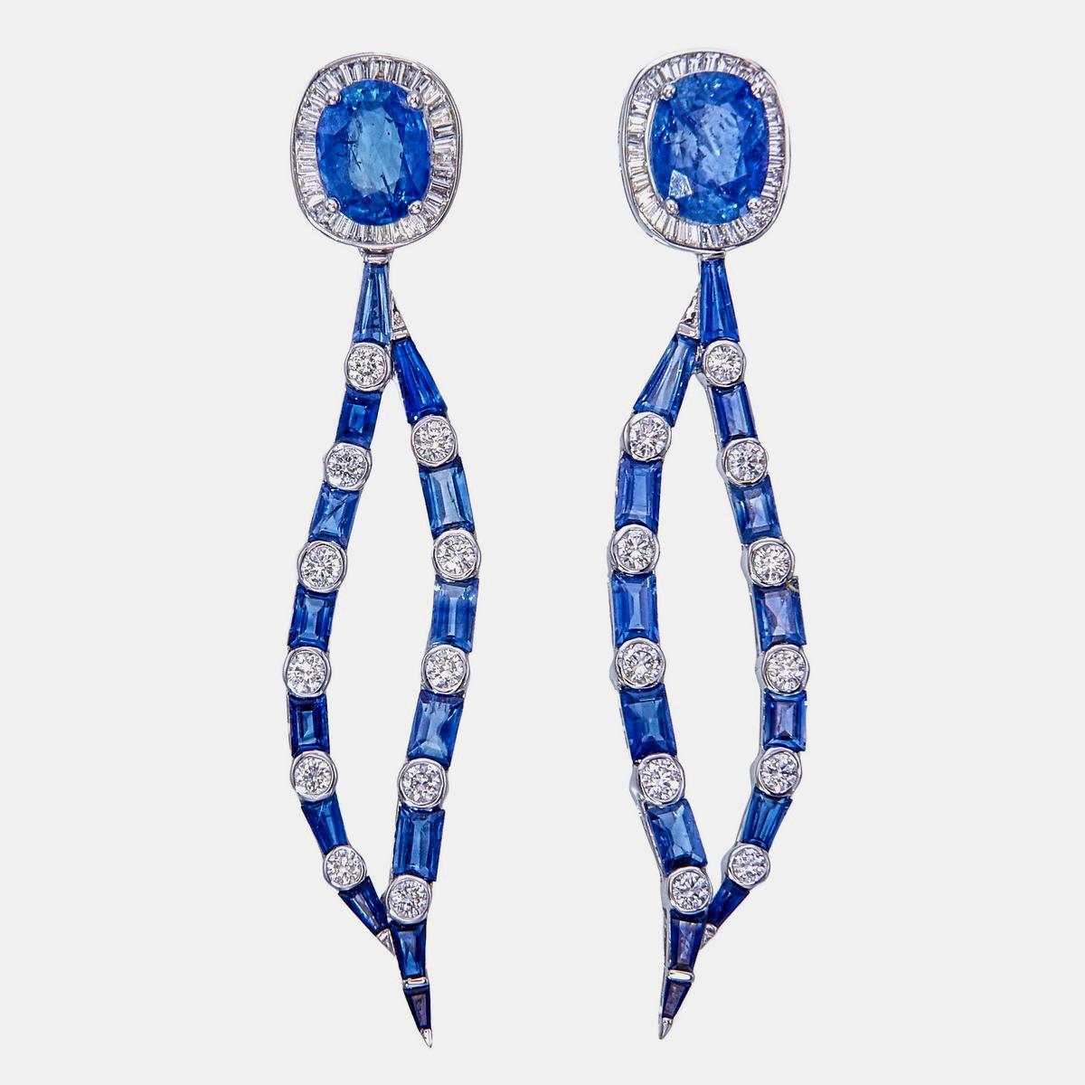 Un elegante paio di orecchini con zaffiri blu e diamanti di REWA Jewell è realizzato in oro bianco 18 carati.

I pezzi centrali sono costituiti da zaffiri blu di forma ovale del peso di circa 2,00 carati e 1,70 carati, circondati da 28 zaffiri blu a