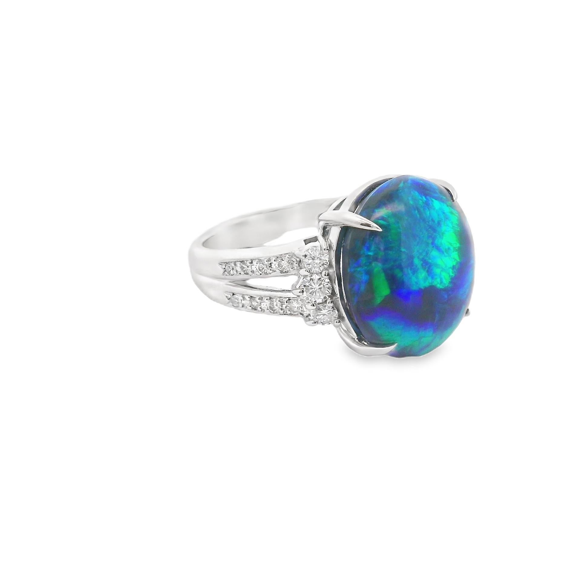 A chic and elegant ring featuring a large and impressive black opal. The natural Australian opal weighs 8.07 carats and has excellent play-of-color as strong flashes of blues and greens dance across the stone. It is complemented by 0.50 carats of