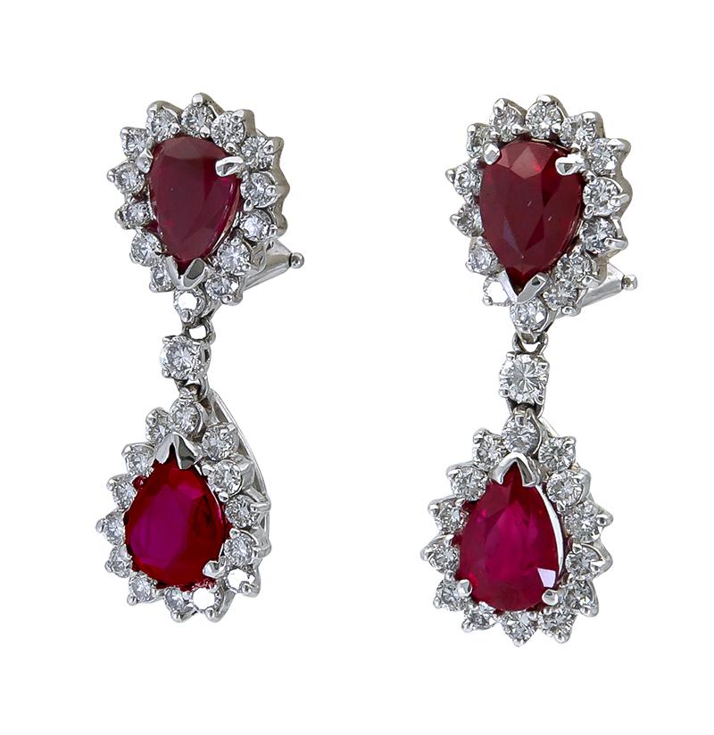 A simple and elegant pair of dangle earrings showcasing pear shape red rubies surrounded by a single row of round brilliant diamonds set in a floral motif. Suspended on another pear shape ruby diamond halo. Made in 18k white gold.

Rubies weigh 8.09