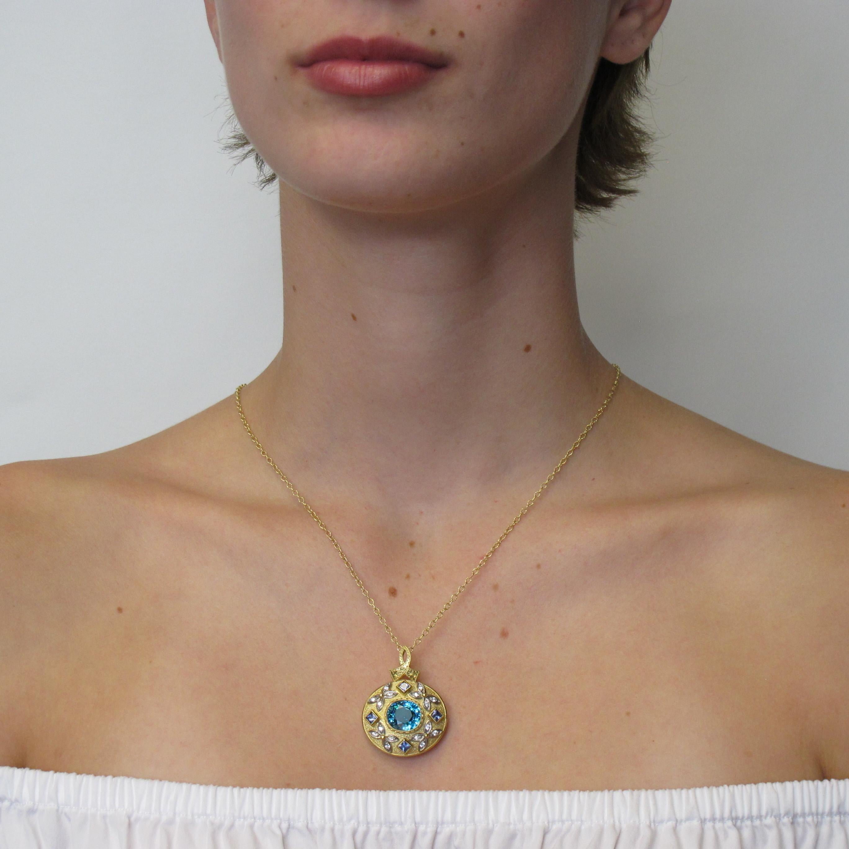 This extraordinary pendant will steal the show! Its detailed design and rich blue zircon gemstone only further highlights the quality craftsmanship we produce here. The cushion cut blue zircon measuring 11x11.5mm (8.09 carats), sixteen round