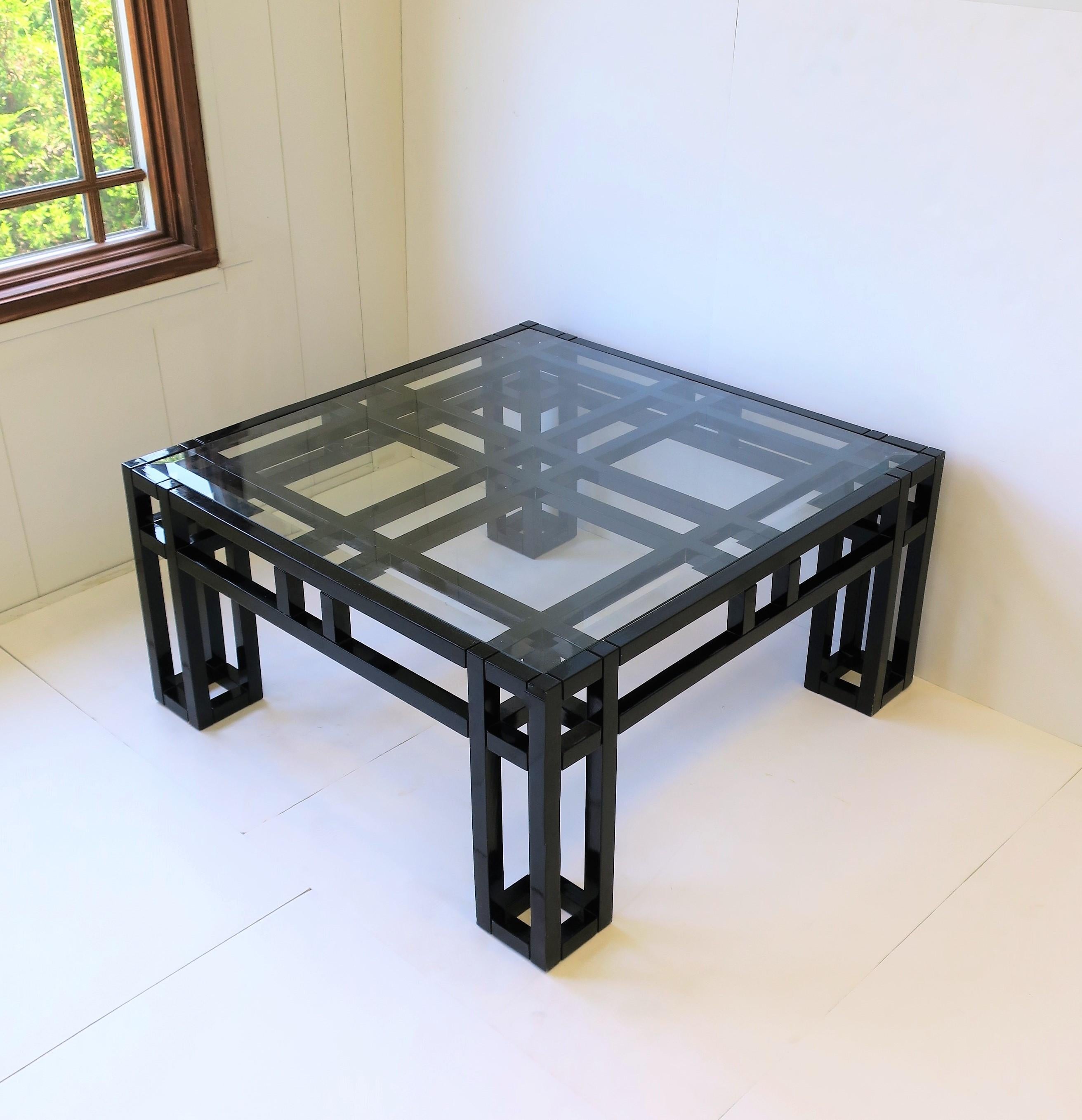A very beautiful geometric square coffee/cocktail table in black lacquer with glass top, Postmodern period, late-20th century, 1980s. Glass top has beveled edge and is 'inset' into coffee table frame. Table measures: 33.38