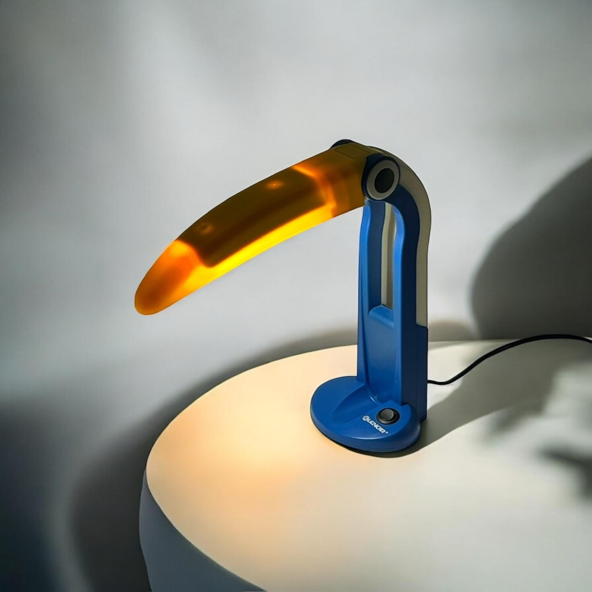 Inject 80s fun into your home or office with the Multicolor Toucan Lamp by HT Huang, produced by Huangslite for Lenoir Italy. This quirky, colorful lamp features a bold blend of blue, yellow, and off-white, perfect for adding a retro vibe to any