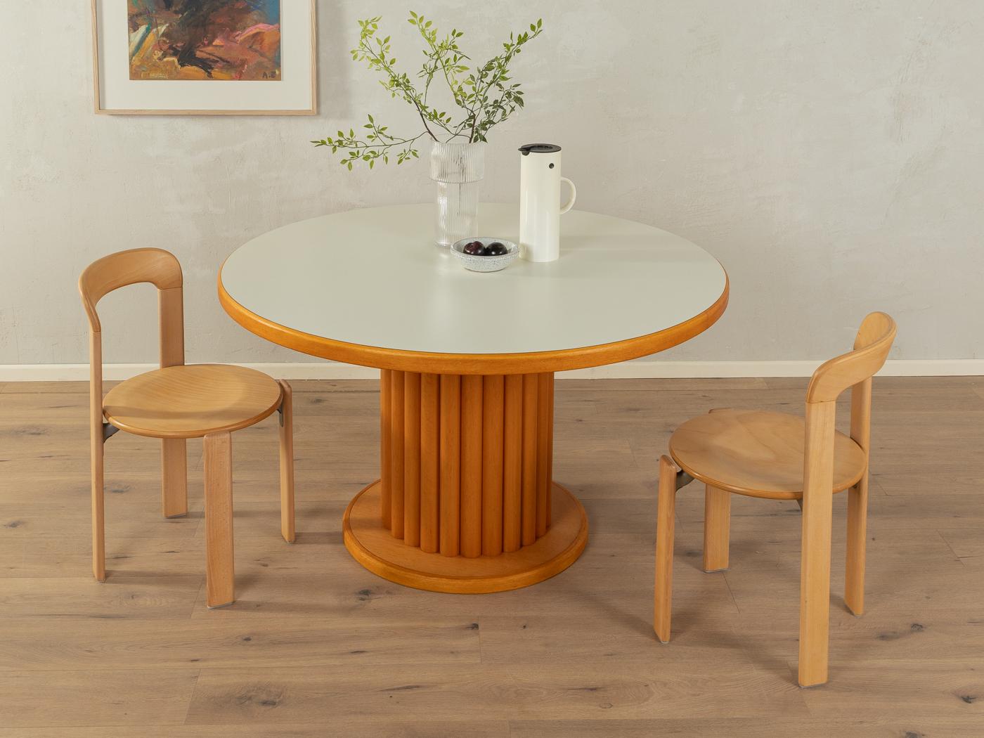 Wonderful dining table by Flötotto from the 1980s. High-quality construction consisting of a Formica coated table top in cream white with solid wood edges and a round base in stained solid beech wood.

Quality Features:
very good