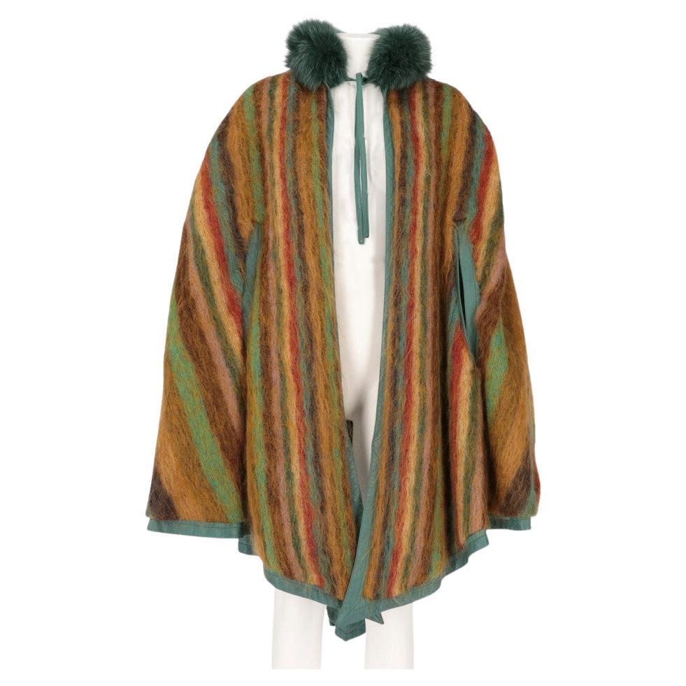 Dior reversible cape in green suede. Collar edged in green fox fur with central ribbon closure. Opening sleeves, tassels and tails in decorative green vision fur. Inner part in multicolored striped mohair wool.

One size

Flat measurements
Height: