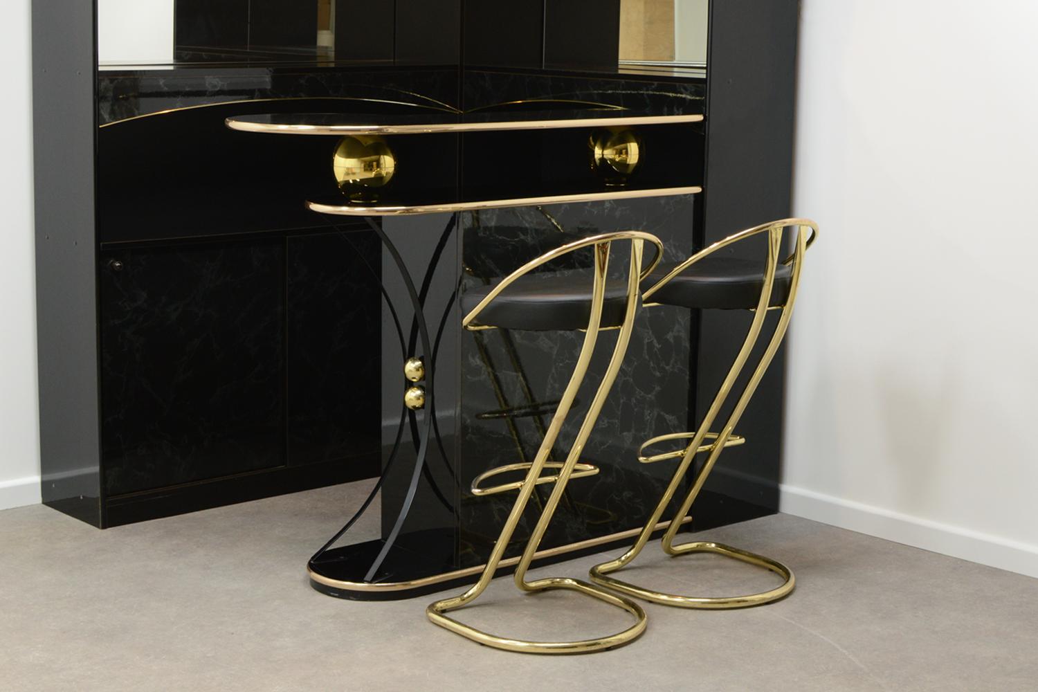 80’s Hollywood regency style home cocktail bar, made in Italy. Gloss black with imitation marble and gold. 2 mirrors, glass shelving, lighting, wine glass hooks and lots of storage. Including 2 bar stools. In good vintage condition. Price for the