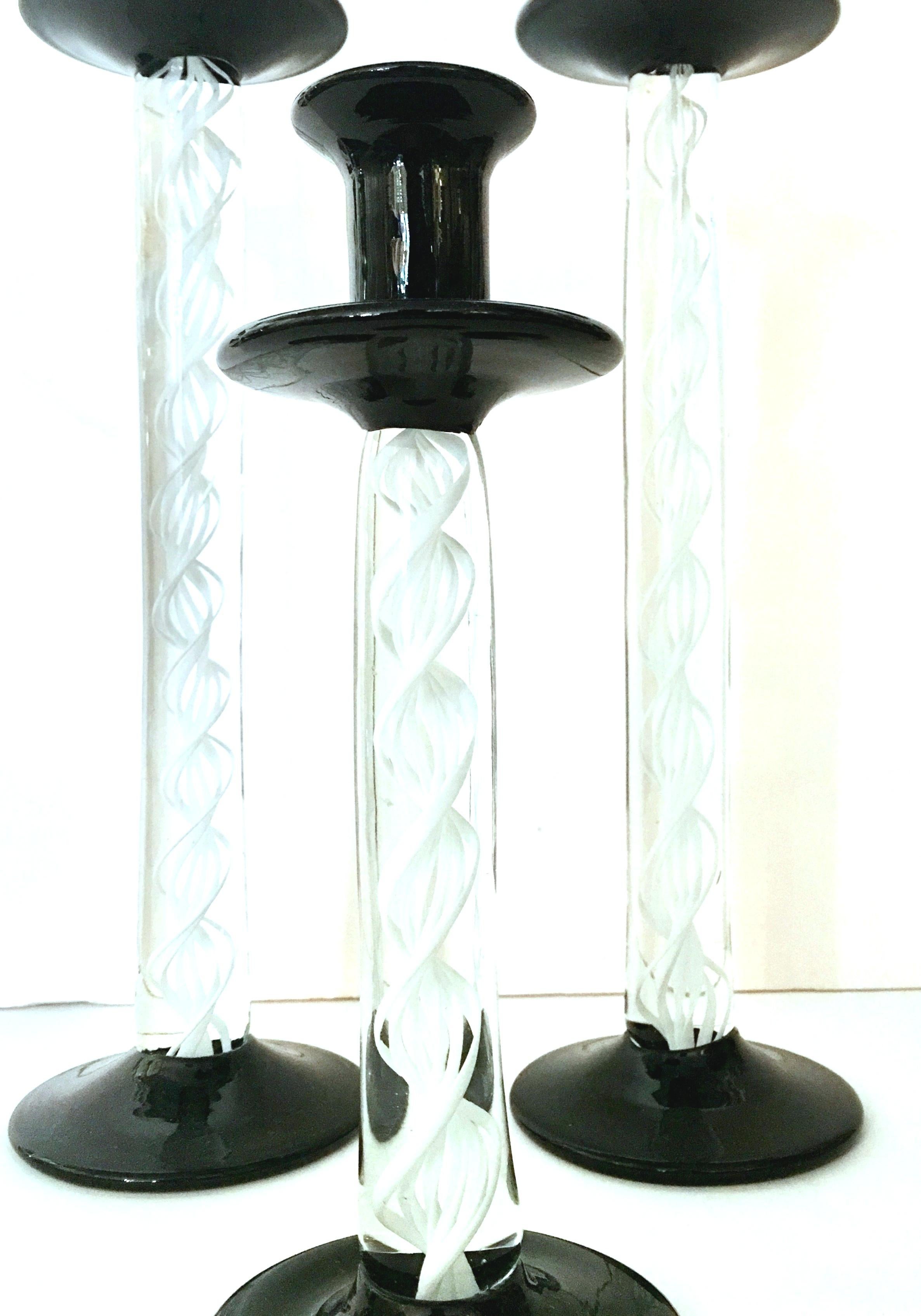 1980s Italian Murano glass candlesticks set of three pieces. Features a translucent body with white cased swirl detail and black foot and holder. Small candlestick measures, 9.5