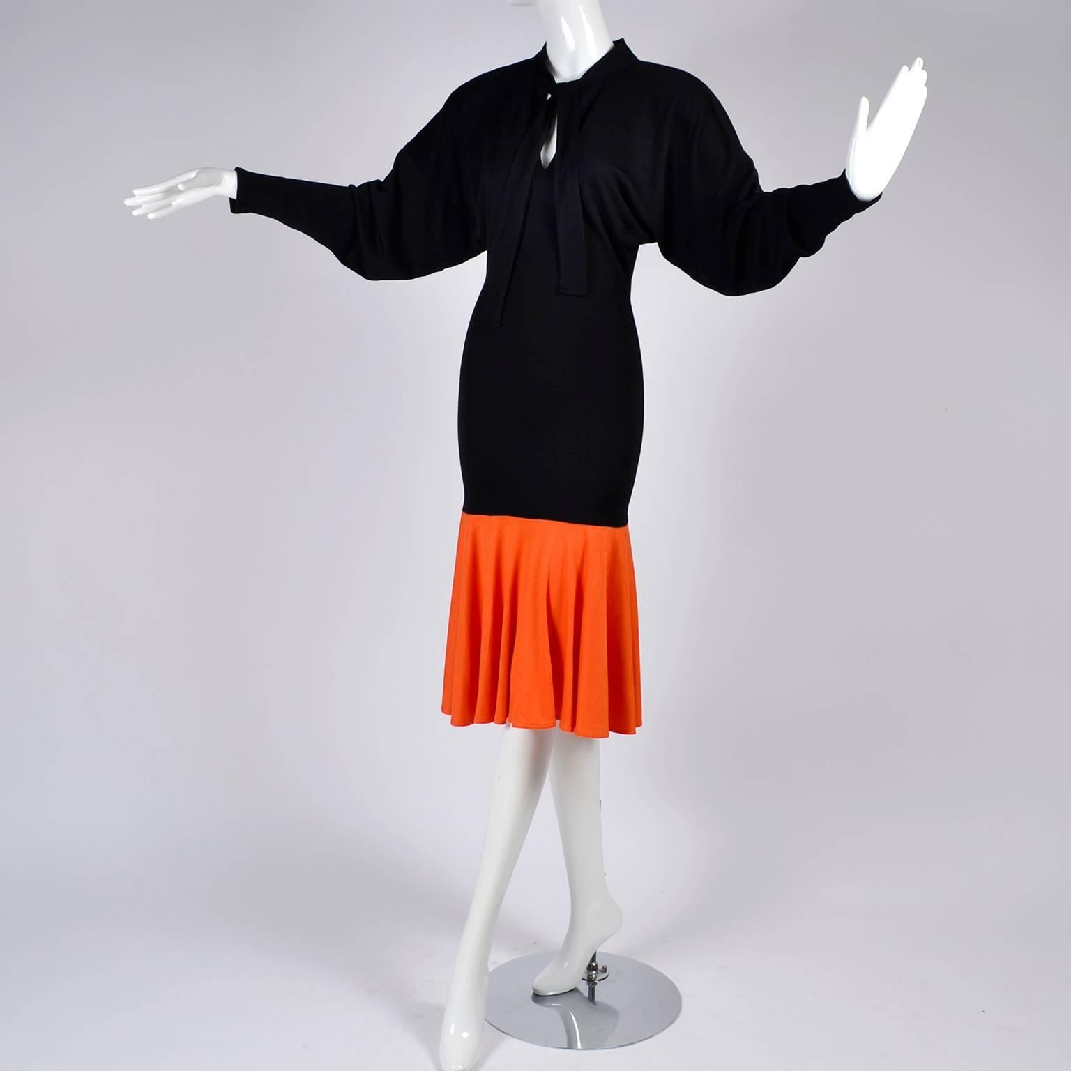 This 1980's vintage Patrick Kelly dress can be worn so effortlessly today! The dress is black jersey with an orange color block flounce hem. The dress has a fitted body, dolman sleeves and a tie at the neck that leaves a keyhole opening. We have